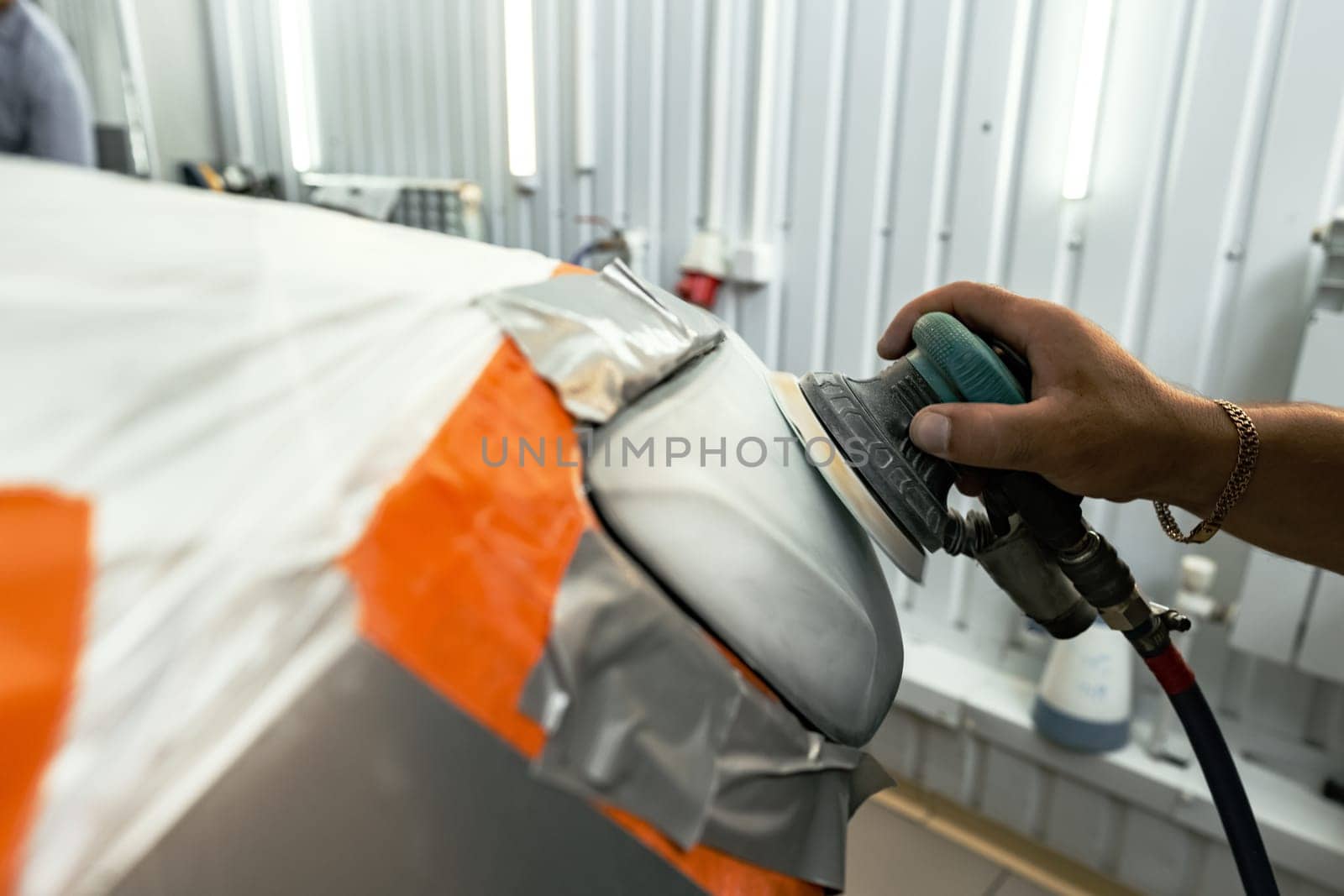Close up photo of car cleaner polishing headlight with polish machine