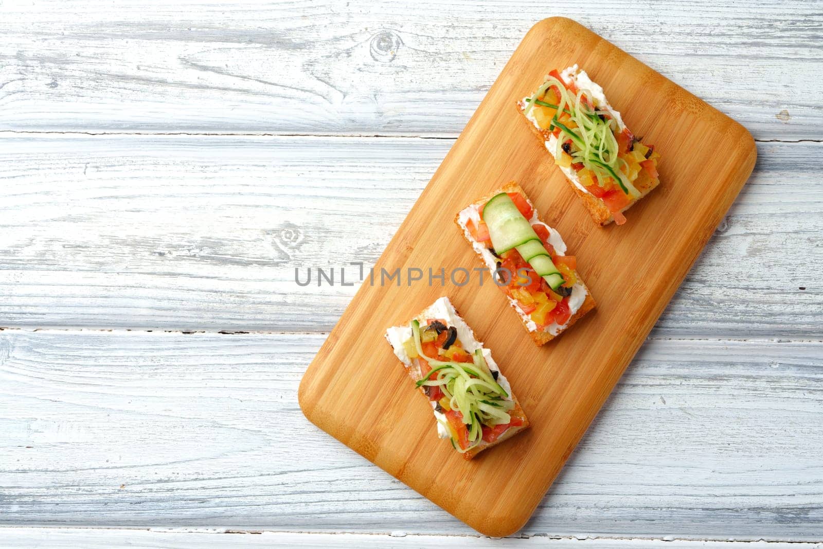 Delicious vegetable bruschetta slices on wooden board close up