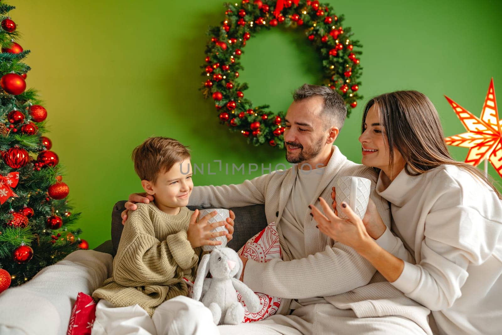 Happy young family sitting on sofa and relaxing at home at Christmas time