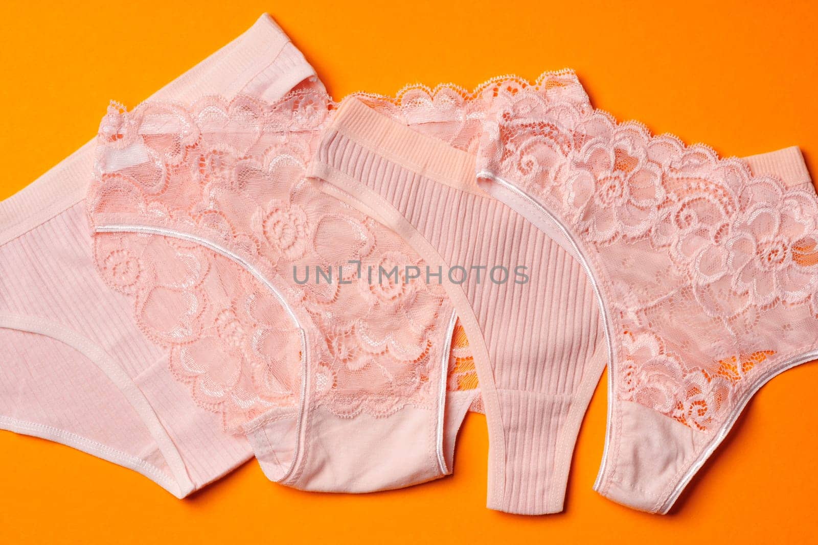 Women's panties on an orange background flat lay top view