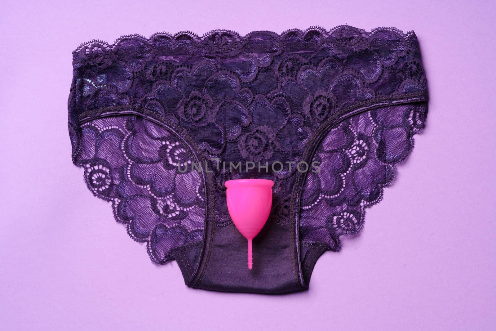 Menstrual cup and panties on paper background, top view