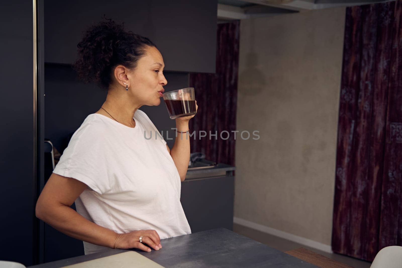 Start your day with energizing freshly brewed coffee. Young woman drinking her morning coffee in the home kitchen