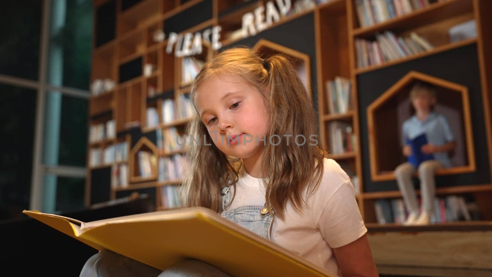 Smart caucasian girl picking reading a book while sitting at library. Erudition. by biancoblue