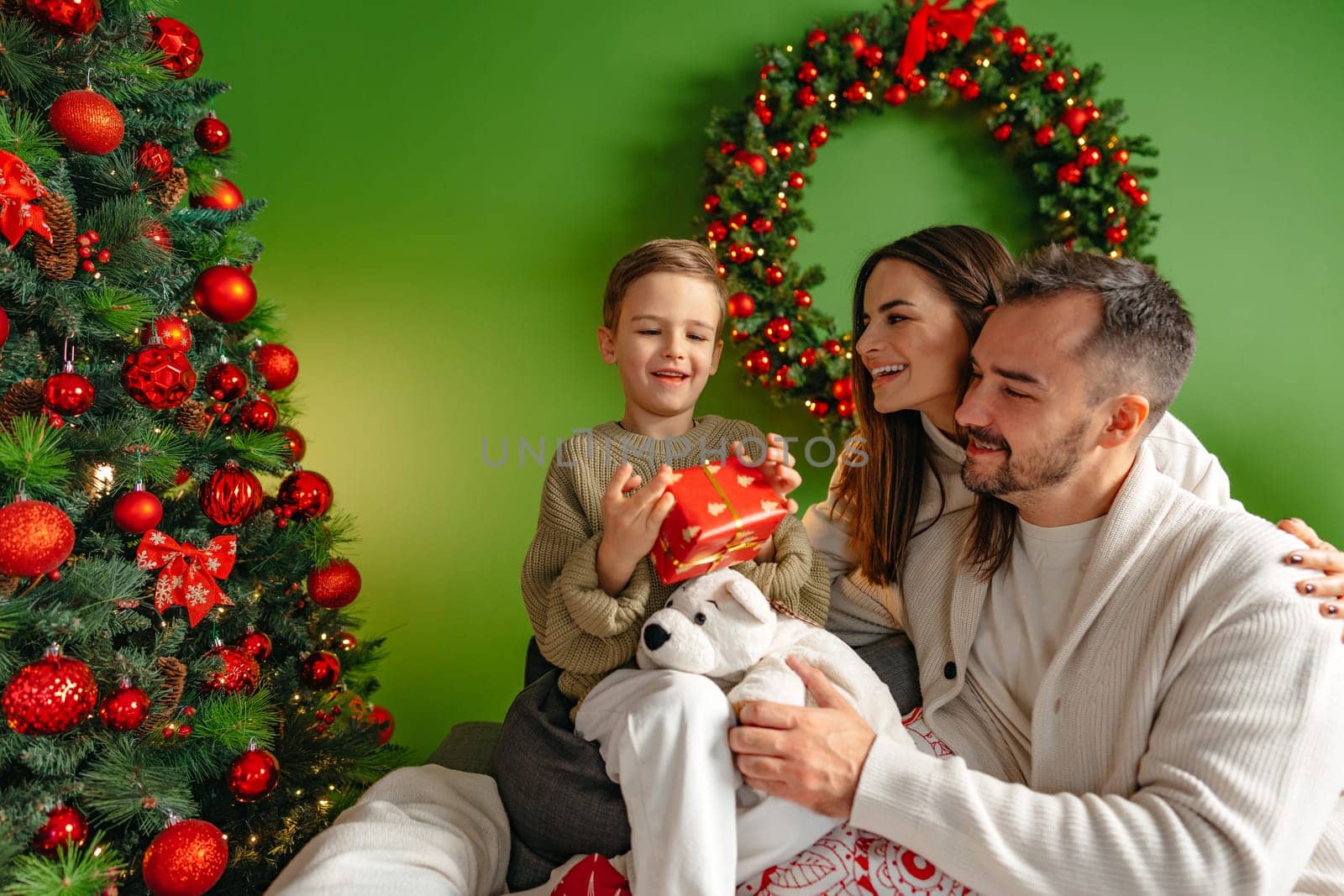 Happy young family sitting on sofa and relaxing at home at Christmas time