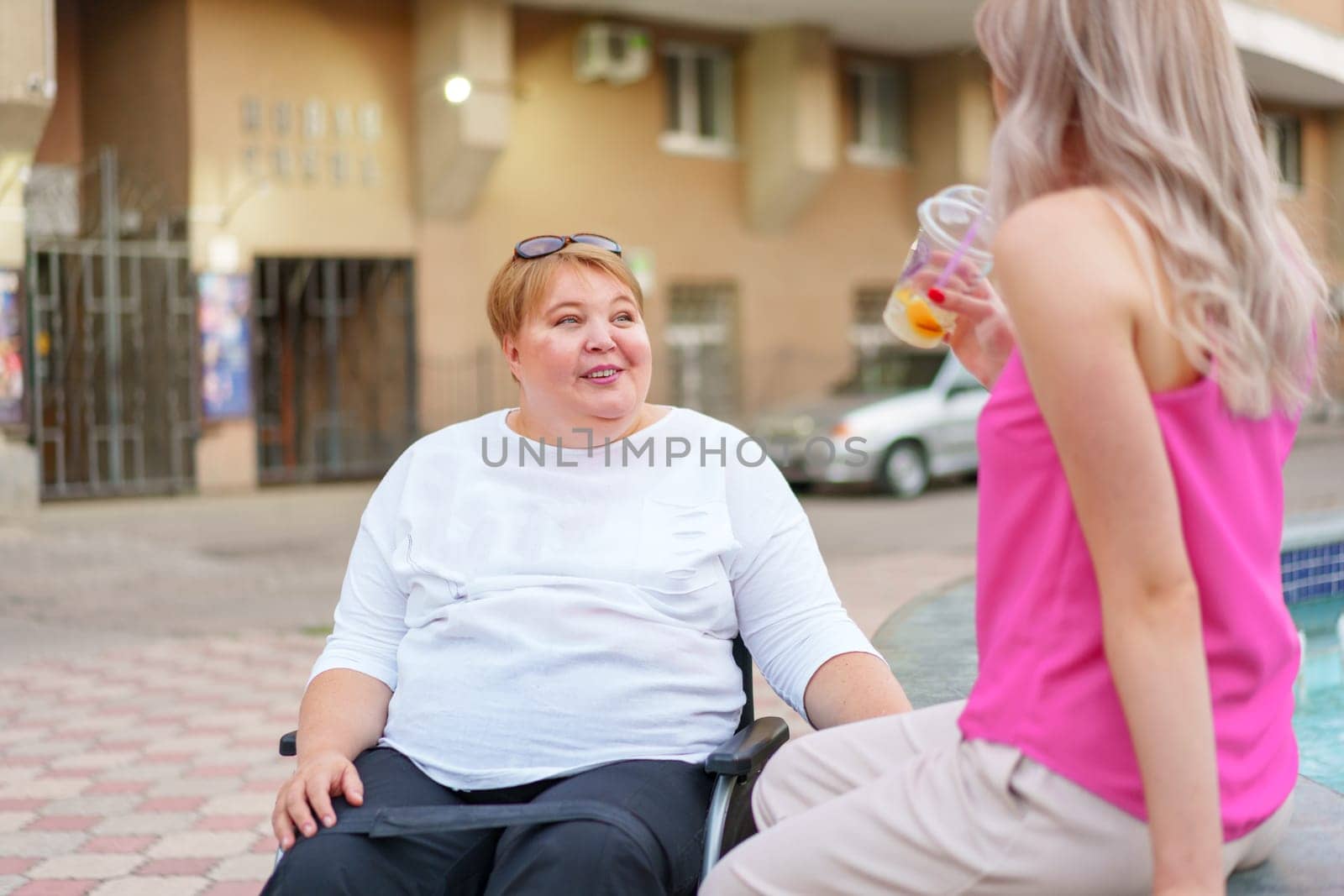 Young daughter taking care of her mother with disability sitting in wheelchair, portrait