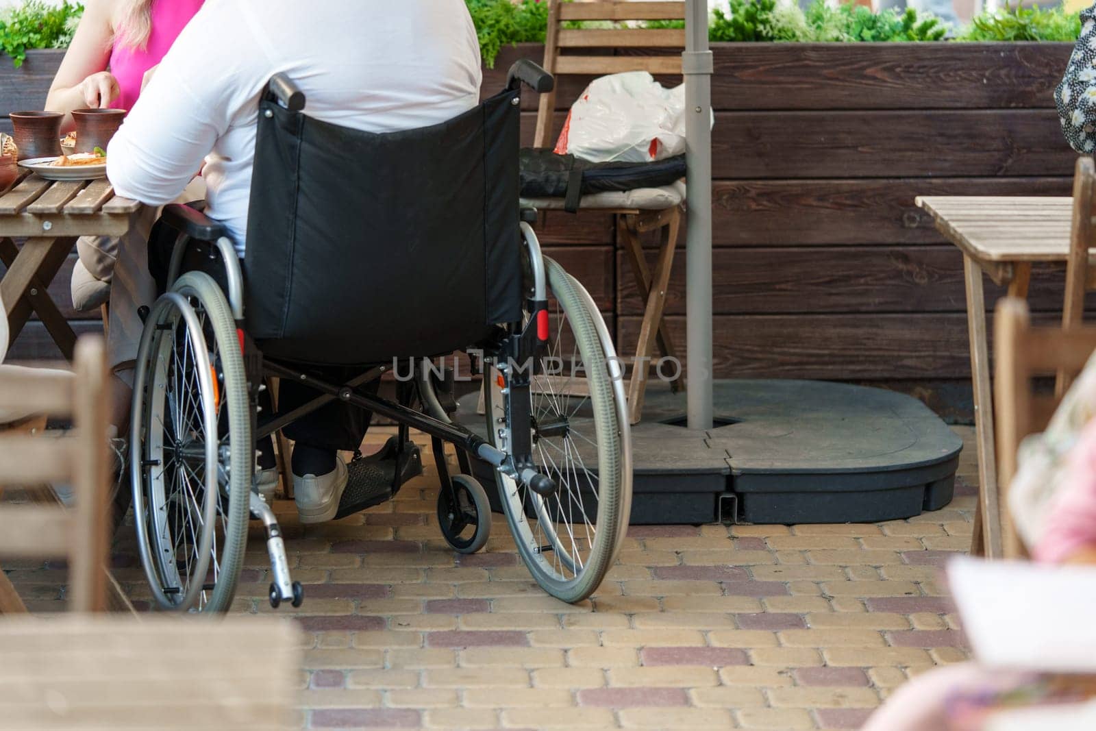Unrecognizable woman with disability sitting in wheelchair in the street close up by Fabrikasimf