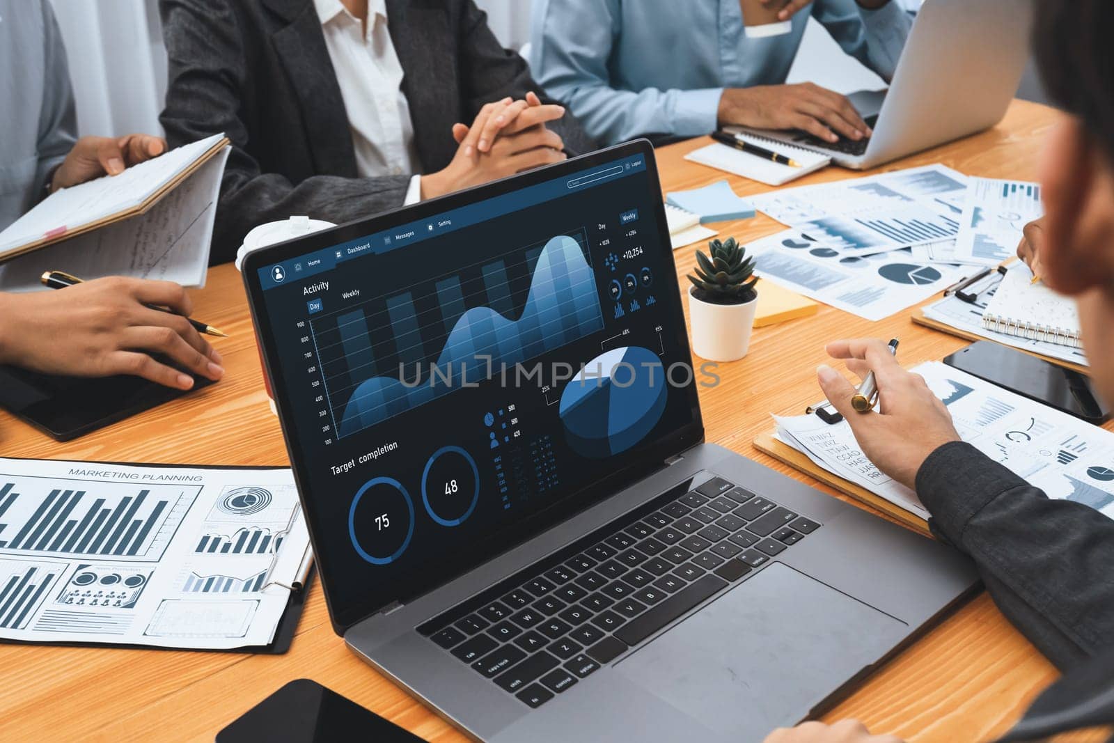 Multiracial analyst team use BI Fintech software to analyze financial data on meeting table. Financial dashboard data display on laptop screen with analyzed chart for marketing indication. Concord