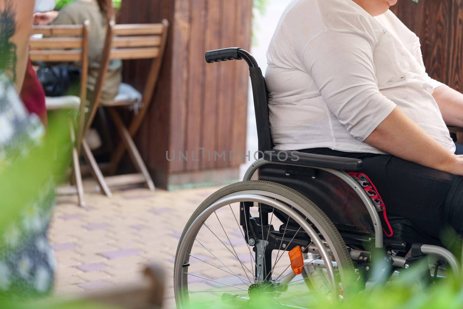 Unrecognizable woman with disability sitting in wheelchair in the street close up photo