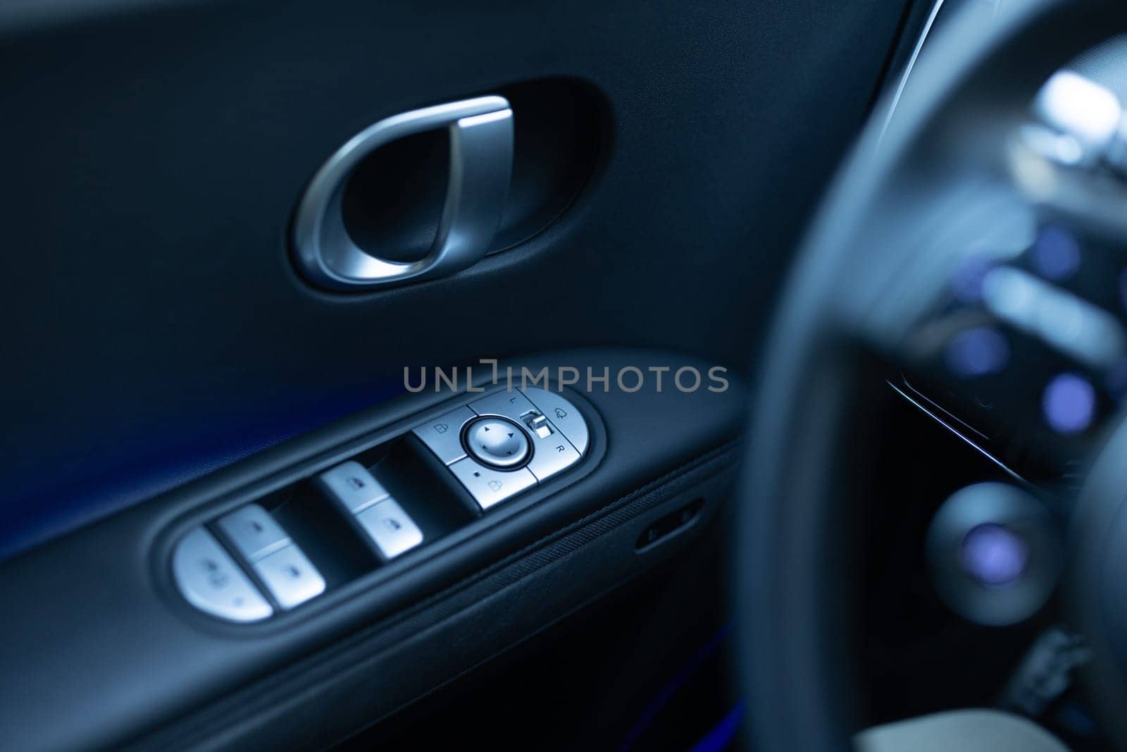 Window control buttons in modern luxury electric car. Car leather interior details of door handle with windows controls and adjustments. Car window controls. Door handle with power window control by uflypro
