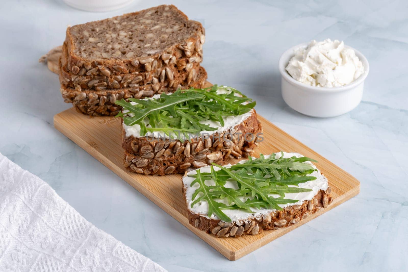 Sandwiches with curd cheese and arugula. Rye bread with seeds.