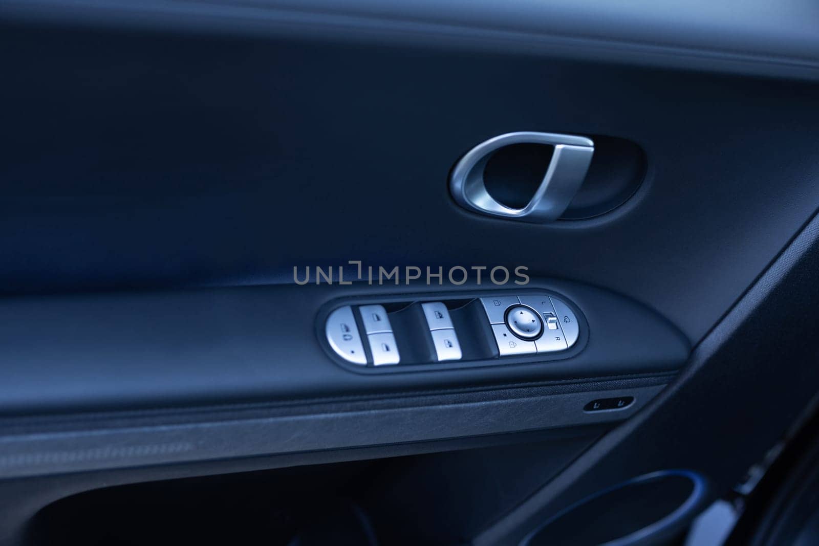 Car window controls. Door handle with power window control. Window control buttons in modern luxury electric car. Car leather interior details of door handle with windows controls and adjustments.