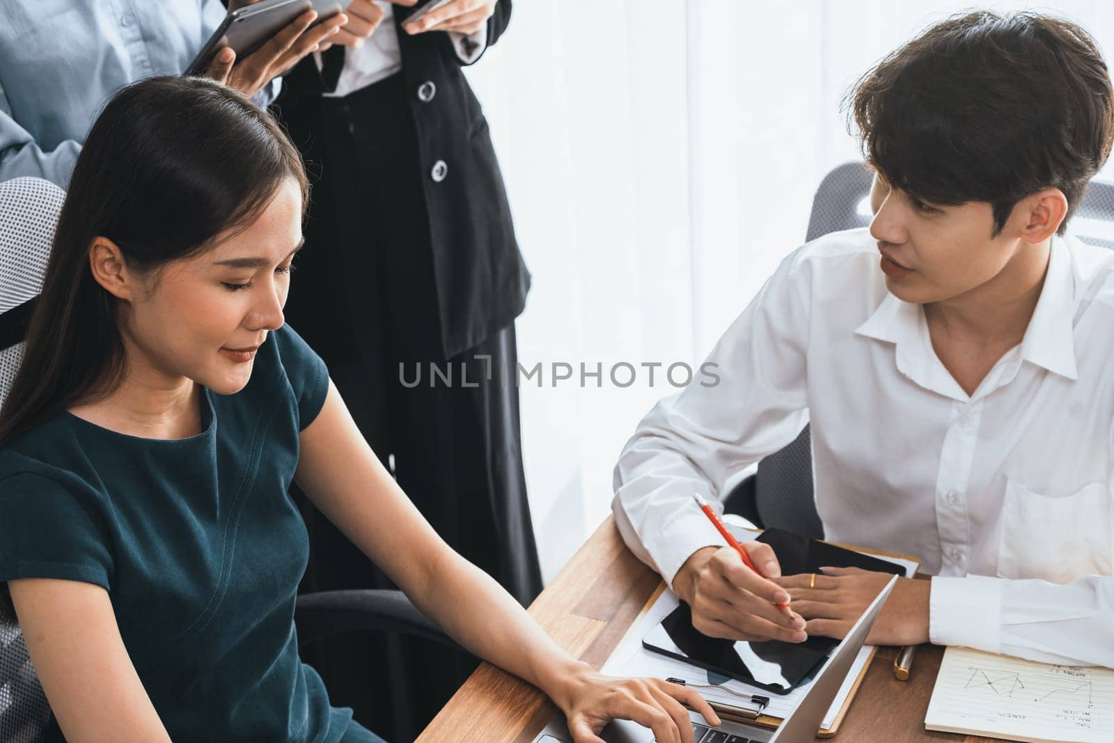 Professional Asian employee work together as team in corporate office, discussing business plans and data to achieve success on desk with laptop. Modern office worker teamwork concept. Concord