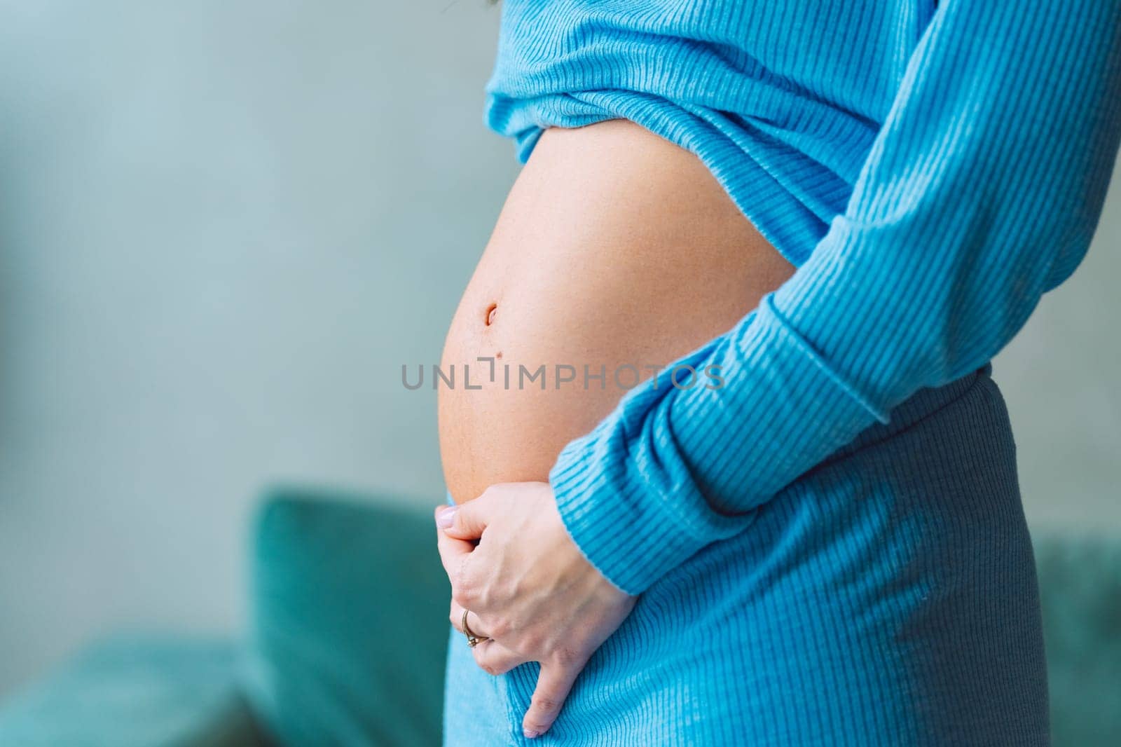 Close-up of young pregnant woman touching her belly and caring about her health. Motherhood and baby expectation concept by DariaKulkova