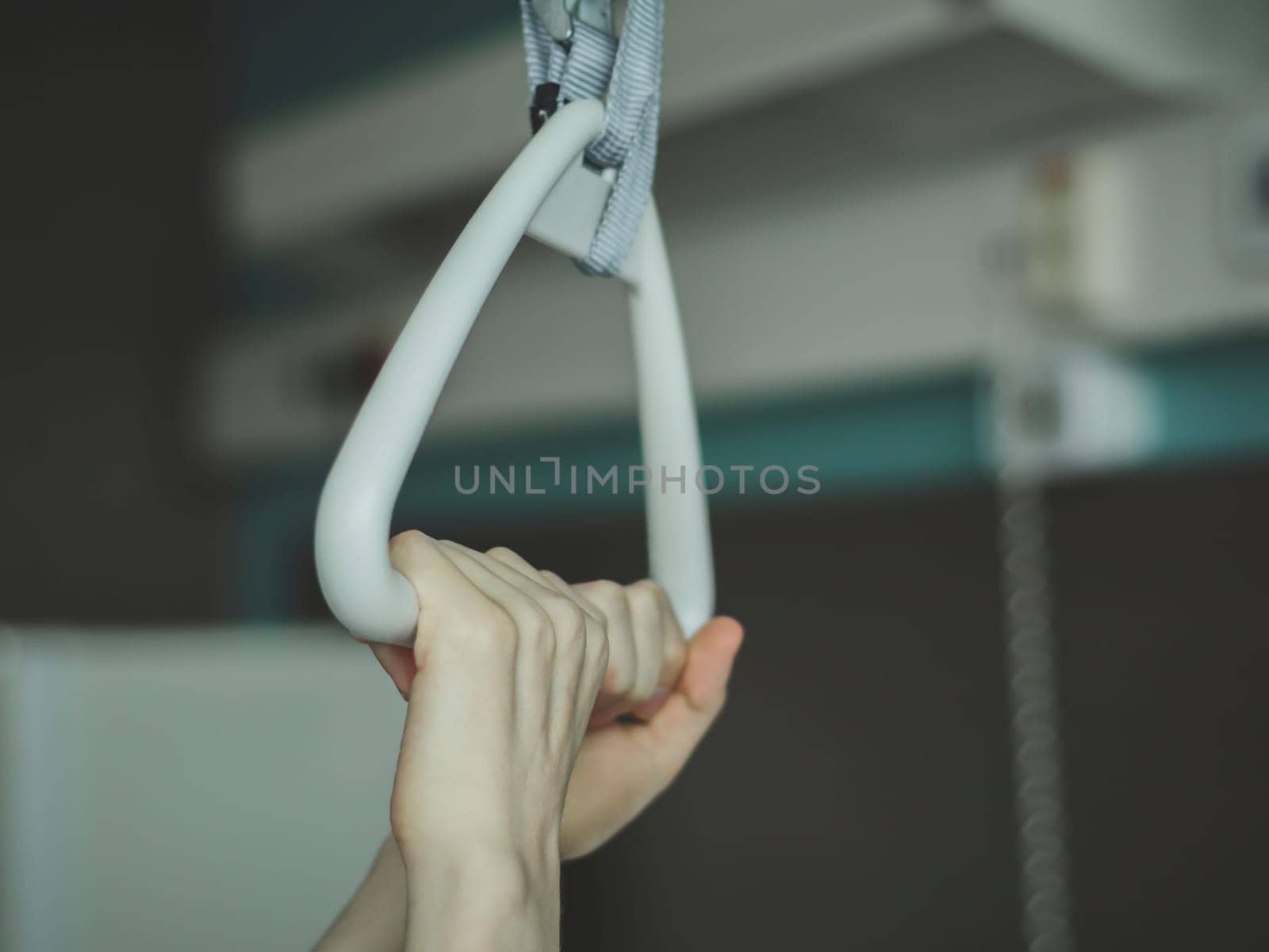 Caucasian guy patient hold with both hands on a triangular therapeutic arc with a gripper by Nataliya