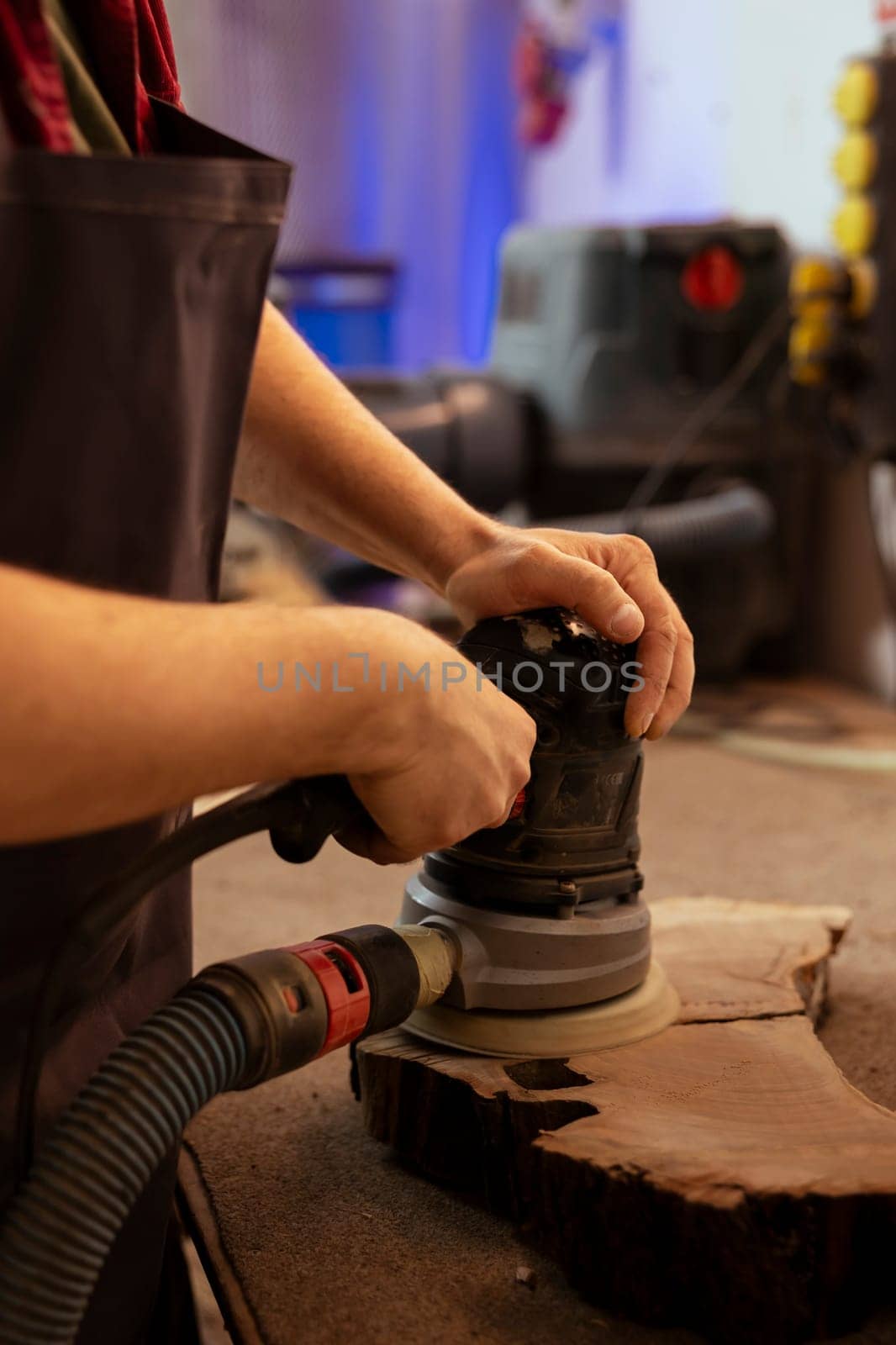 Manufacturer using angle grinder on lumber block to smooth surfaces by abrasion with sandpaper. Man using orbital sander gear for furniture assembling job in assembly shop