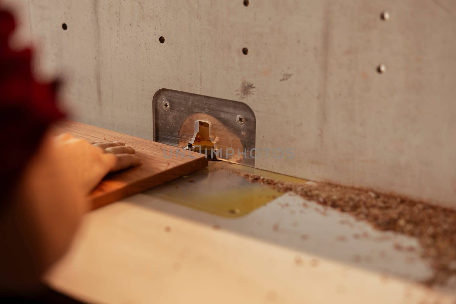 Joiner using wood shaper to perform manufacturing tasks, close up shot by DCStudio