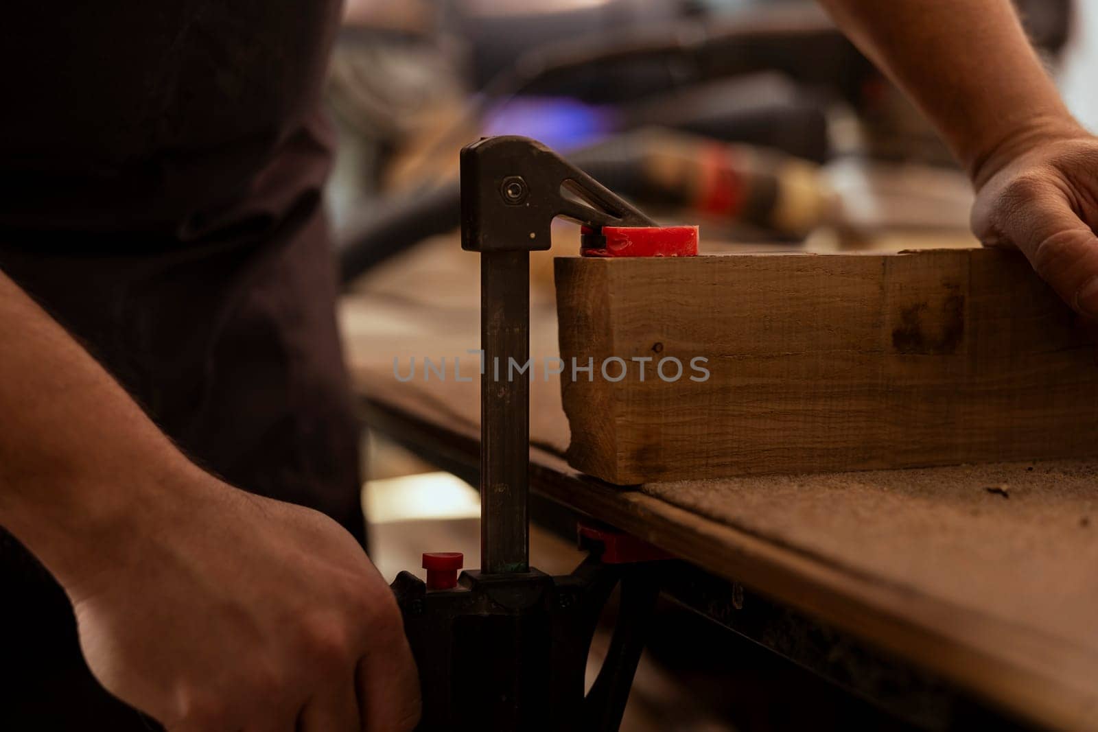 Carpenter using bench vise to hold timber block, starting furniture assembling by DCStudio