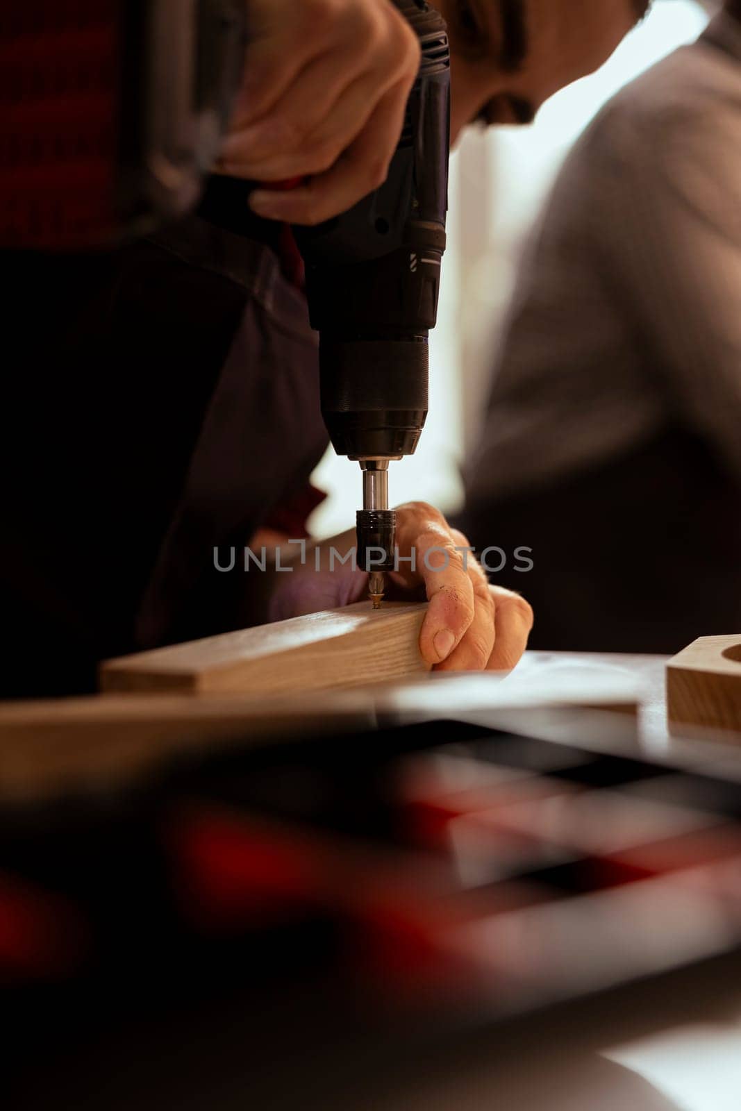 Manufacturer in carpentry shop using power drill to create holes by DCStudio