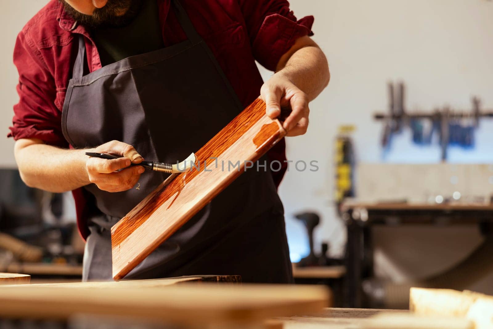 Carpenter applying wax on wooden surface to prevent damage by DCStudio