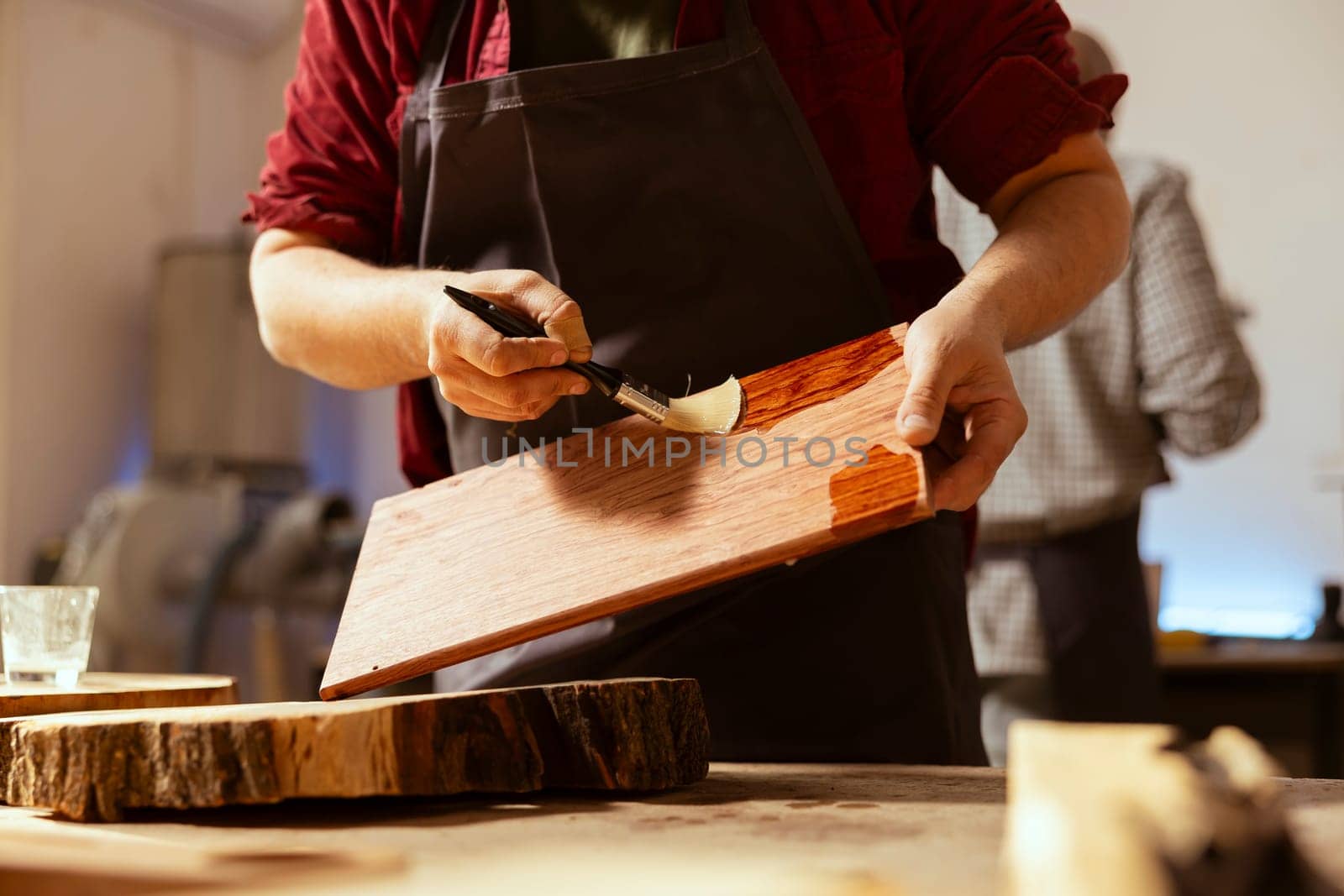 Woodworking specialist applying varnish on wood to build up protective layer. Carpenter in assembly shop lacquering wooden board after sanding surface to ensure smoothness, close up shot