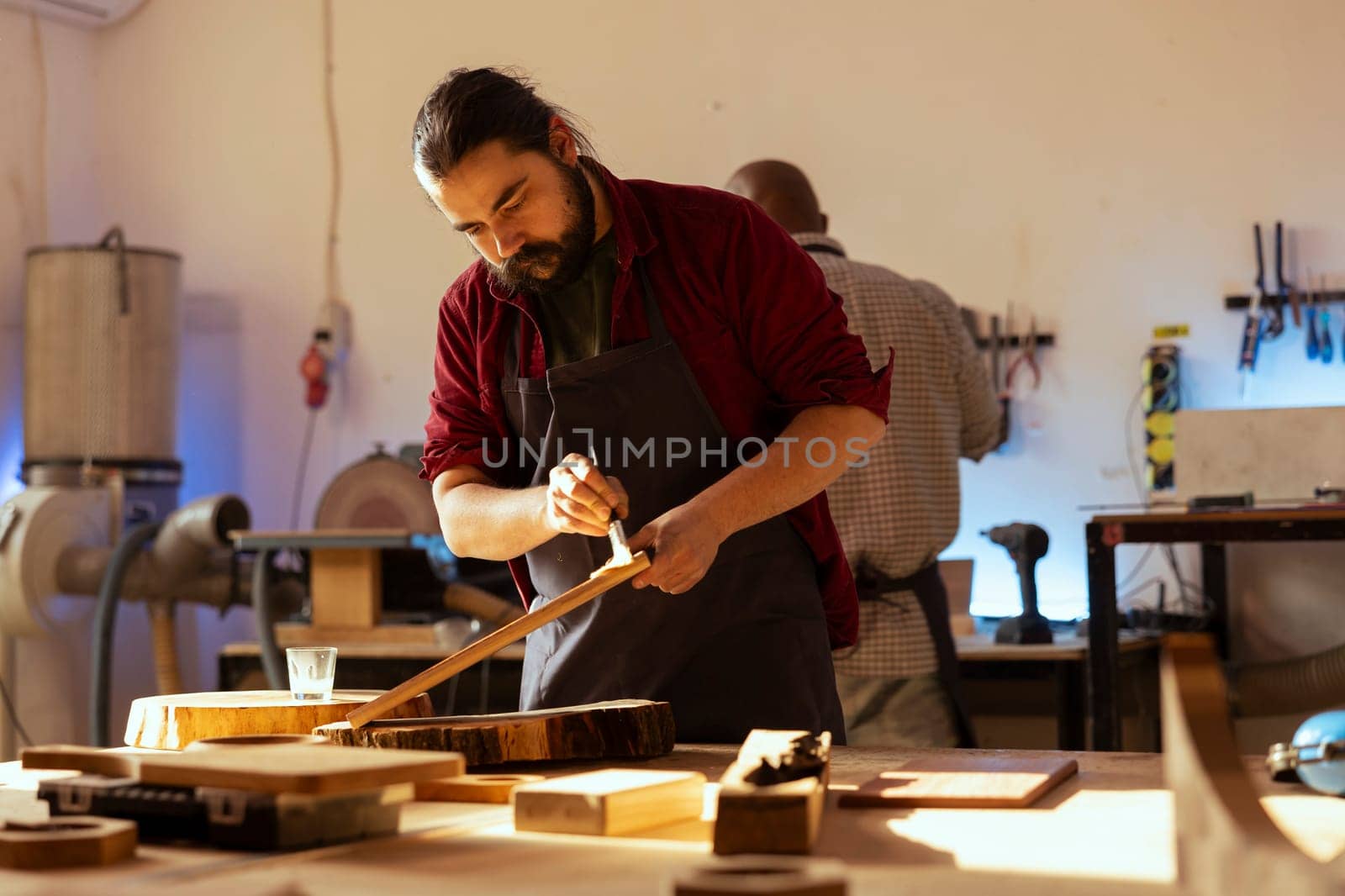 Carpenter brushing varnish on wood in multiple coats to build up protective layer. Woodworker in assembly shop lacquering plank after sanding surface to ensure smoothness