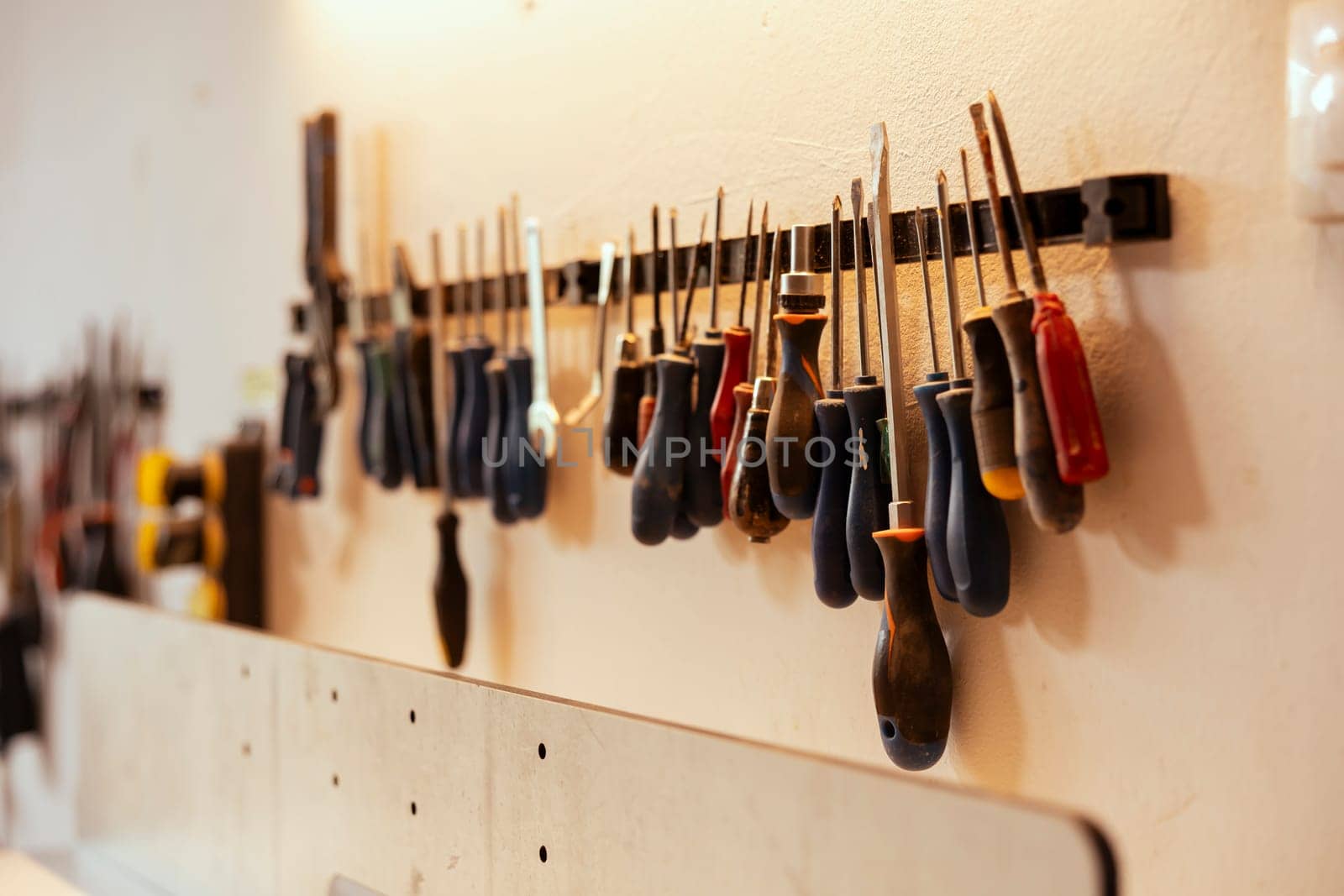 Close up shot of various woodworking tools on rack in workshop used for repairing or creating wooden objects. Chisels, screwdrivers, wrench and pliers on wall in carpentry studio
