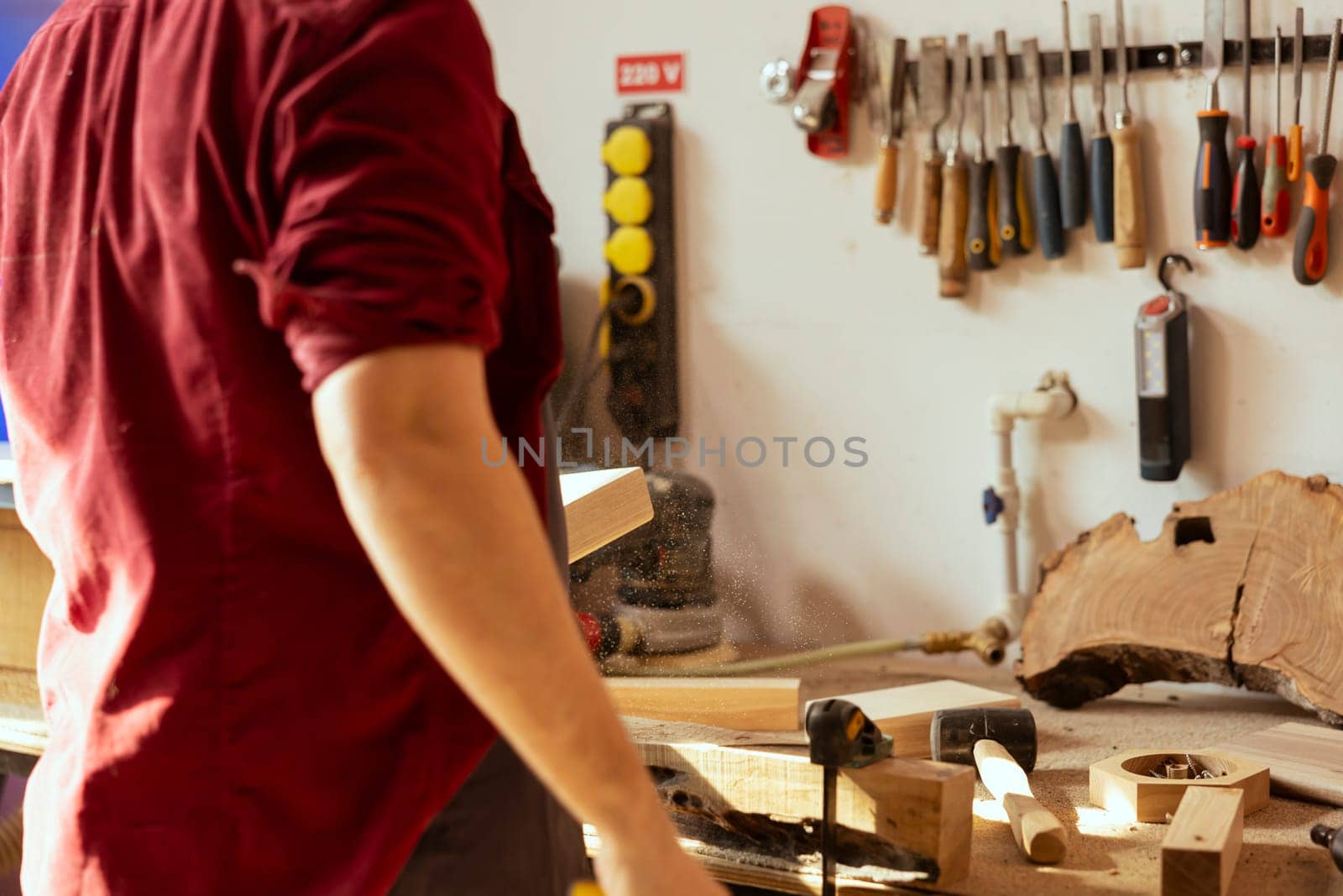 Artisan working in studio using sanding block to remove imperfections on wood piece. Creative person enjoying diy hobby, using coarse grade sandpaper to do manual sanding on lumber