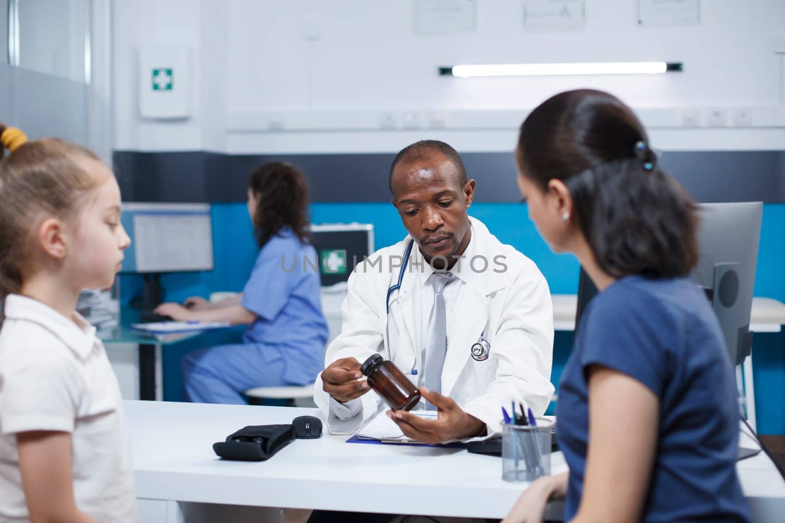 Concerns regarding mother and daughter are discussed with a healthcare expert. While holding a prescription bottle, African American physician describes medication and diagnosis to Caucasian patients.