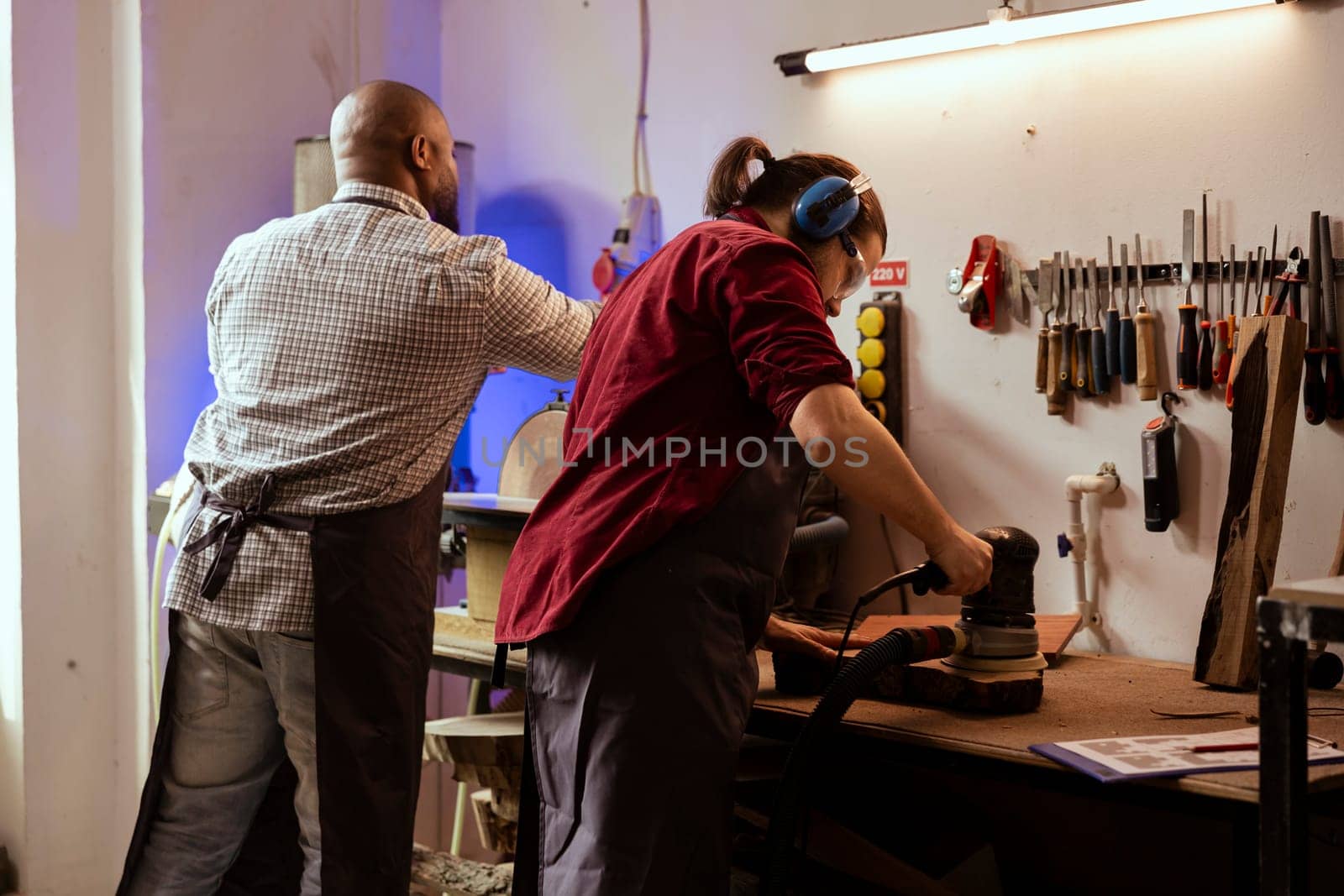 Teamworking employees in assembly shop using angle grinder by DCStudio