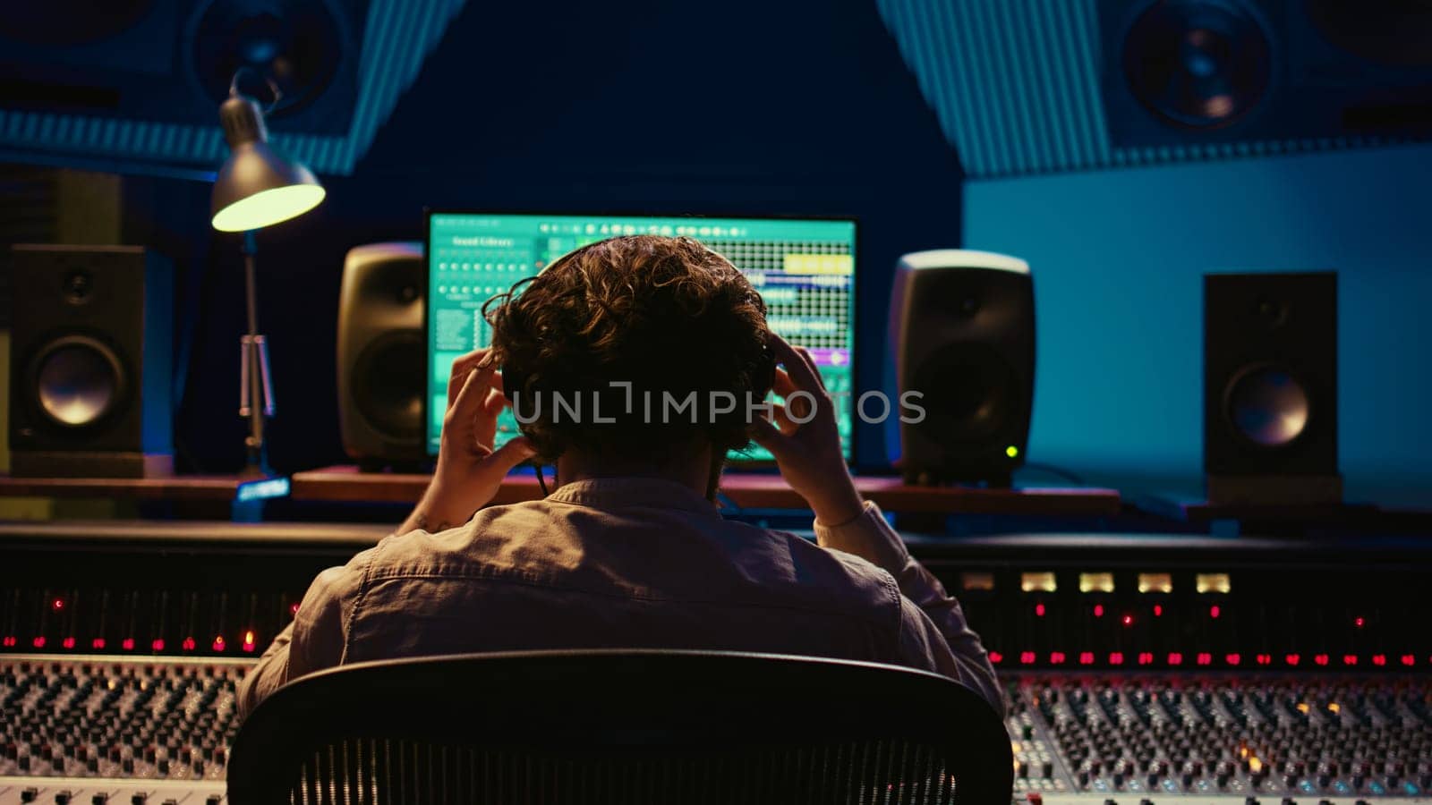 Mixer producer develops audio by editing recordings and integrating additional sounds using buttons on mixing console. Engineer in sound design uses motorized faders at production studio. Camera B.