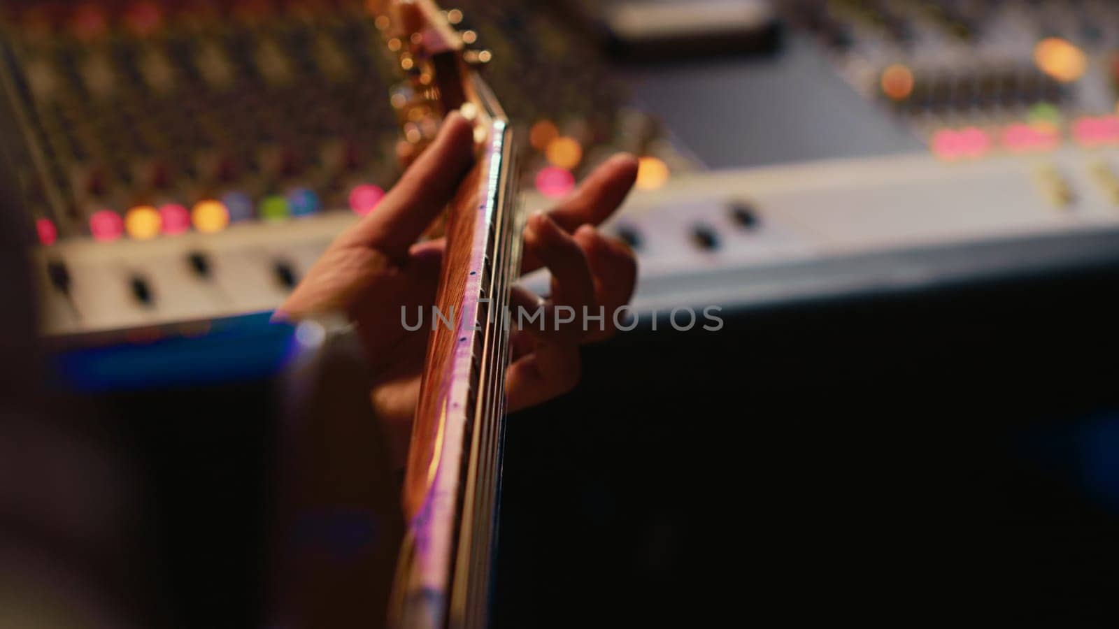Musician singer recording a new song on his electro acoustic guitar, creating new music in professional studio control room. Artist doing live performance with instrument. Close up. Camera A.