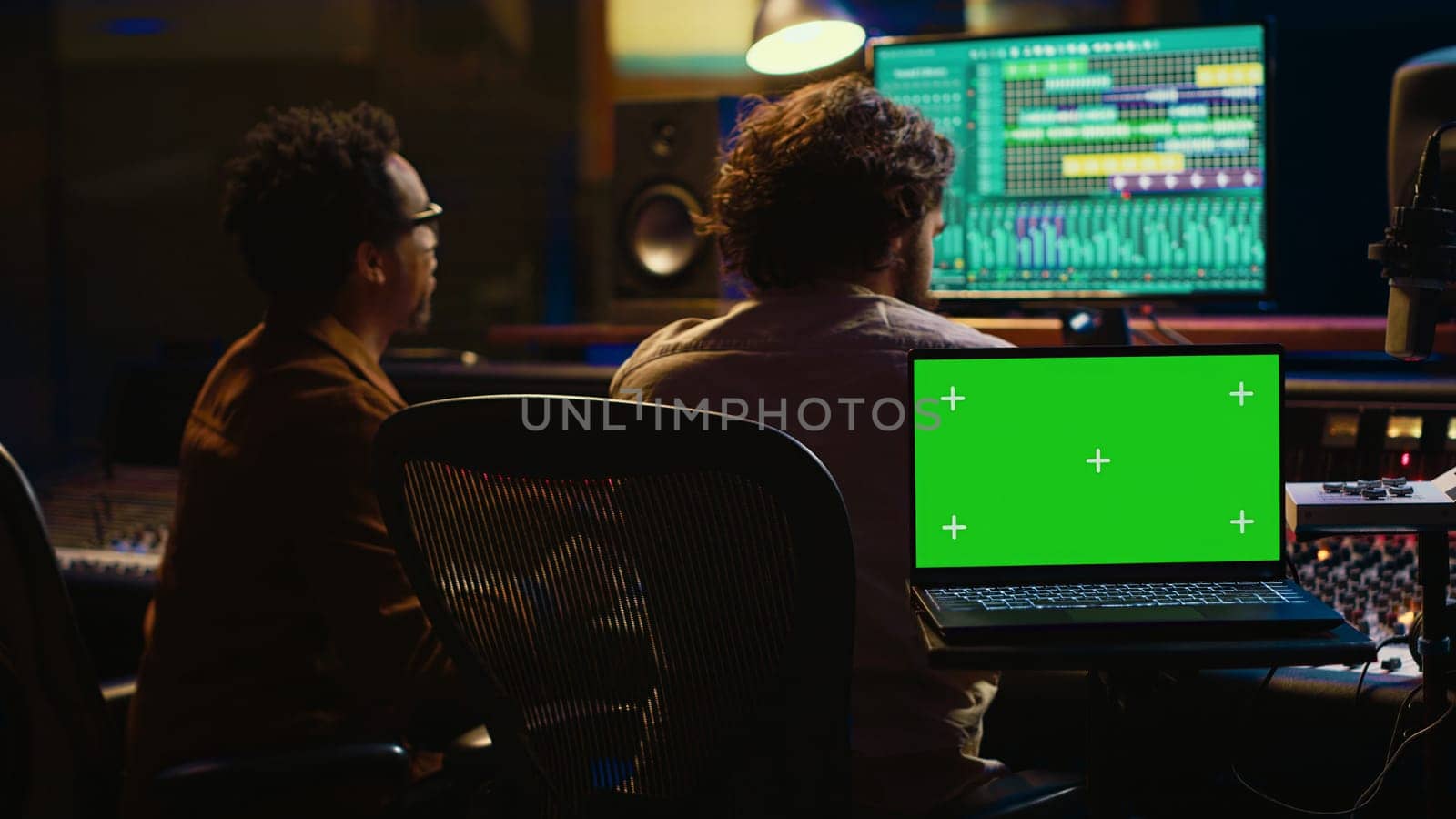 Team of artist and music producer work with mockup display, processing and mixing sounds in professional studio control room. Experts producing tracks by using technical equipment. Camera A.