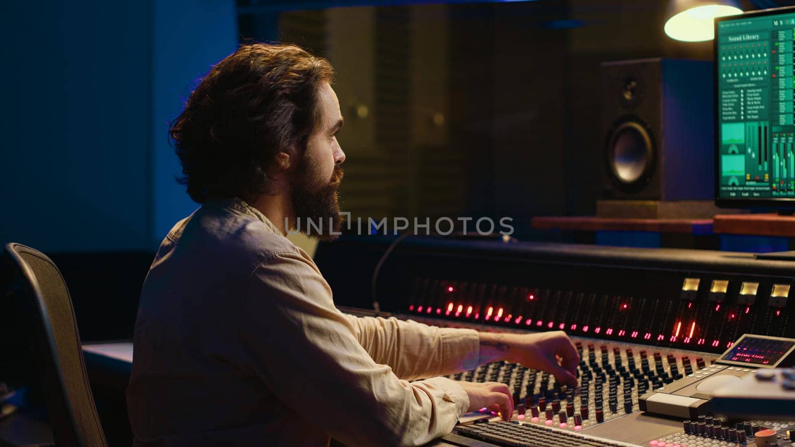 Control room sound engineer editing music with sliders and knobs, working on post production in professional soundproof studio. Technician producing songs on stereo mixing console. Camera A.