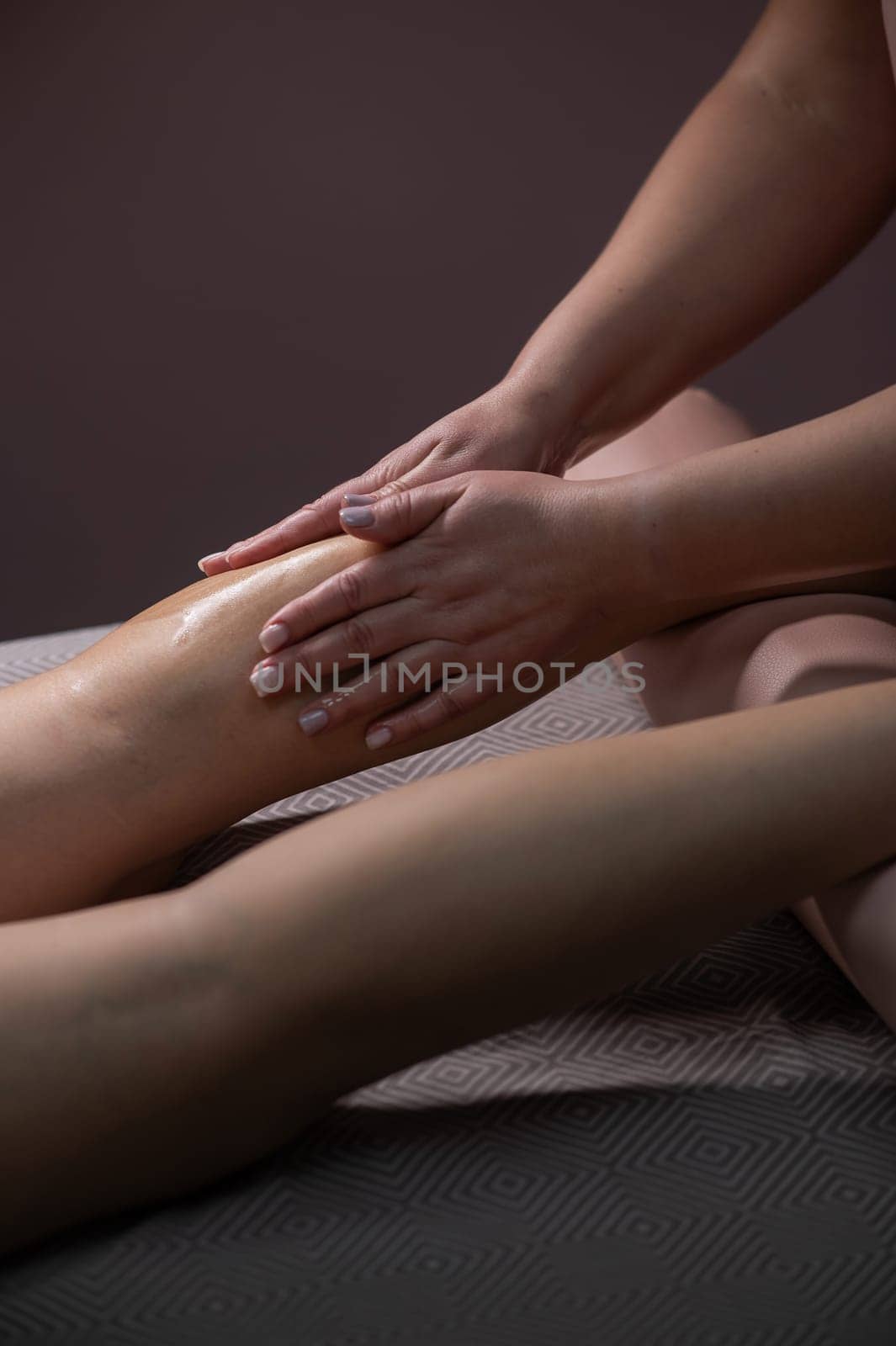 Close-up of a woman's leg massage in a salon. Vertical photo