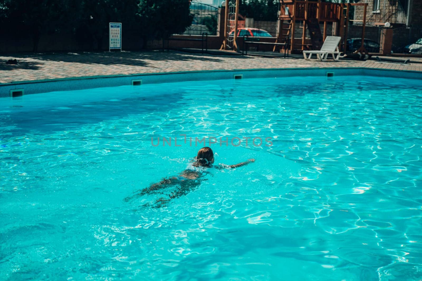 A woman is swimming in a pool. The water is clear and calm. The woman is wearing a black swimsuit