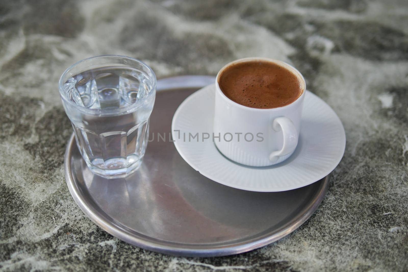 a cup of turkish coffee and glass of water on tiles background by towfiq007