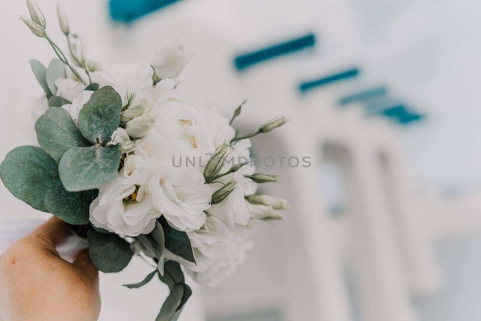 A bouquet of white flowers is being held by a person. The flowers are arranged in a way that they are not too close to each other, giving the impression of a beautiful and elegant arrangement
