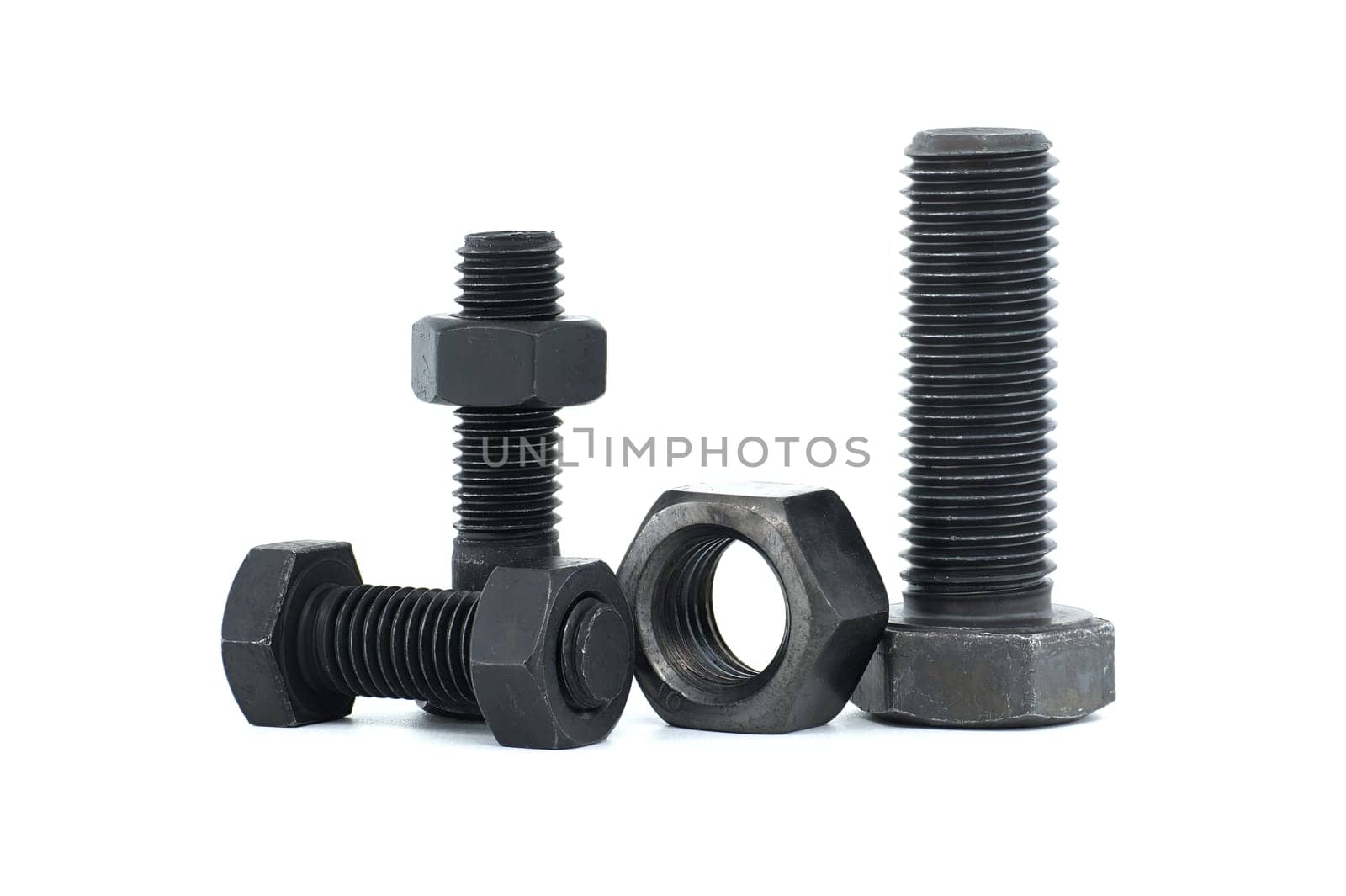 Orderly arrangement of dark-colored metal of hex bolts and nuts include long and shorter parts, placed against a clean, white background