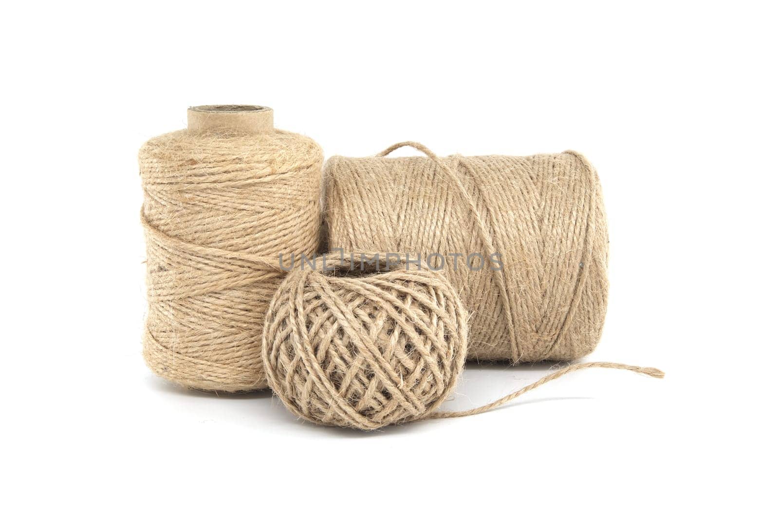 Three spools of jute twine isolated on white background, each varying in size, made from natural jute materials