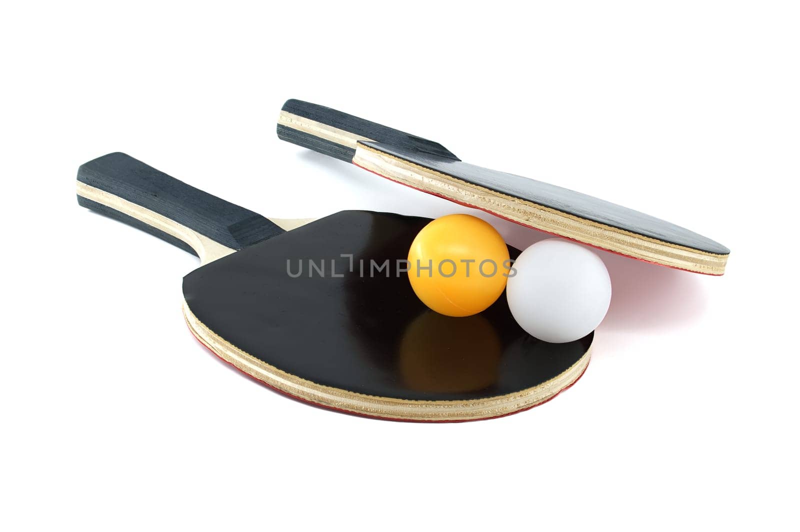 Isolated on a white background are two ping pong paddles and a ping pong ball, with one racket's surface appearing in red and the other in black