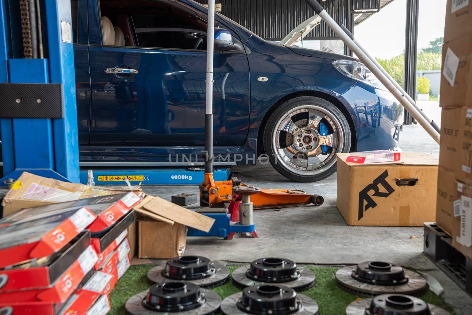 Bangkok, Thailand - February 4, 2023 : Unidentified car mechanic or serviceman disassembly and checking a disc brake and asbestos brake pads for fix and repair problem at car garage or repair shop