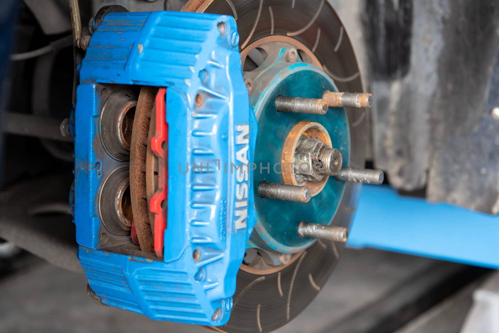 Bangkok, Thailand - February 4, 2023 : Unidentified car mechanic or serviceman disassembly and checking a disc brake and asbestos brake pads for fix and repair problem at car garage or repair shop