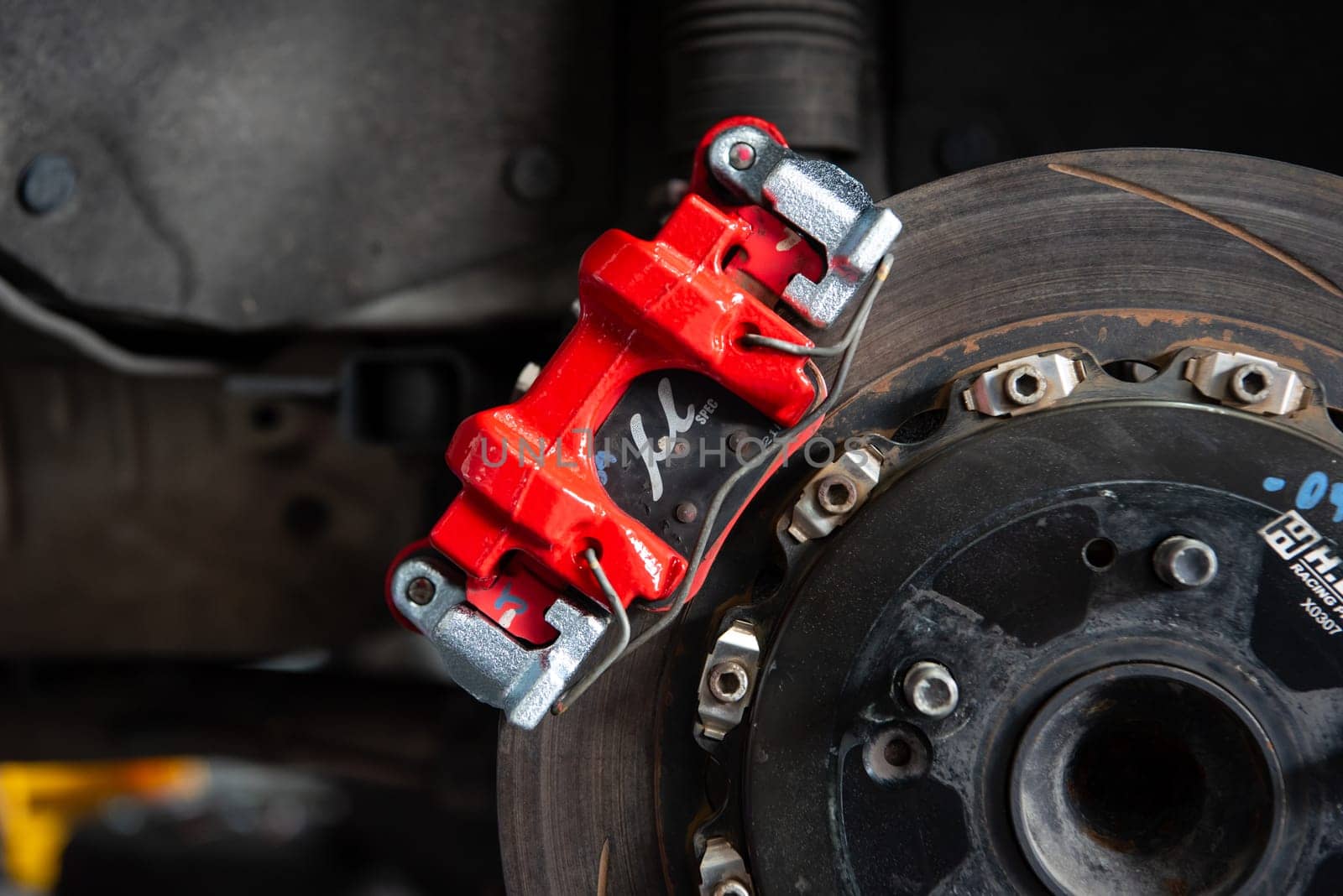 Bangkok, Thailand - February 4, 2023 : Unidentified car mechanic or serviceman disassembly and checking a disc brake and asbestos brake pads for fix and repair problem at car garage or repair shop