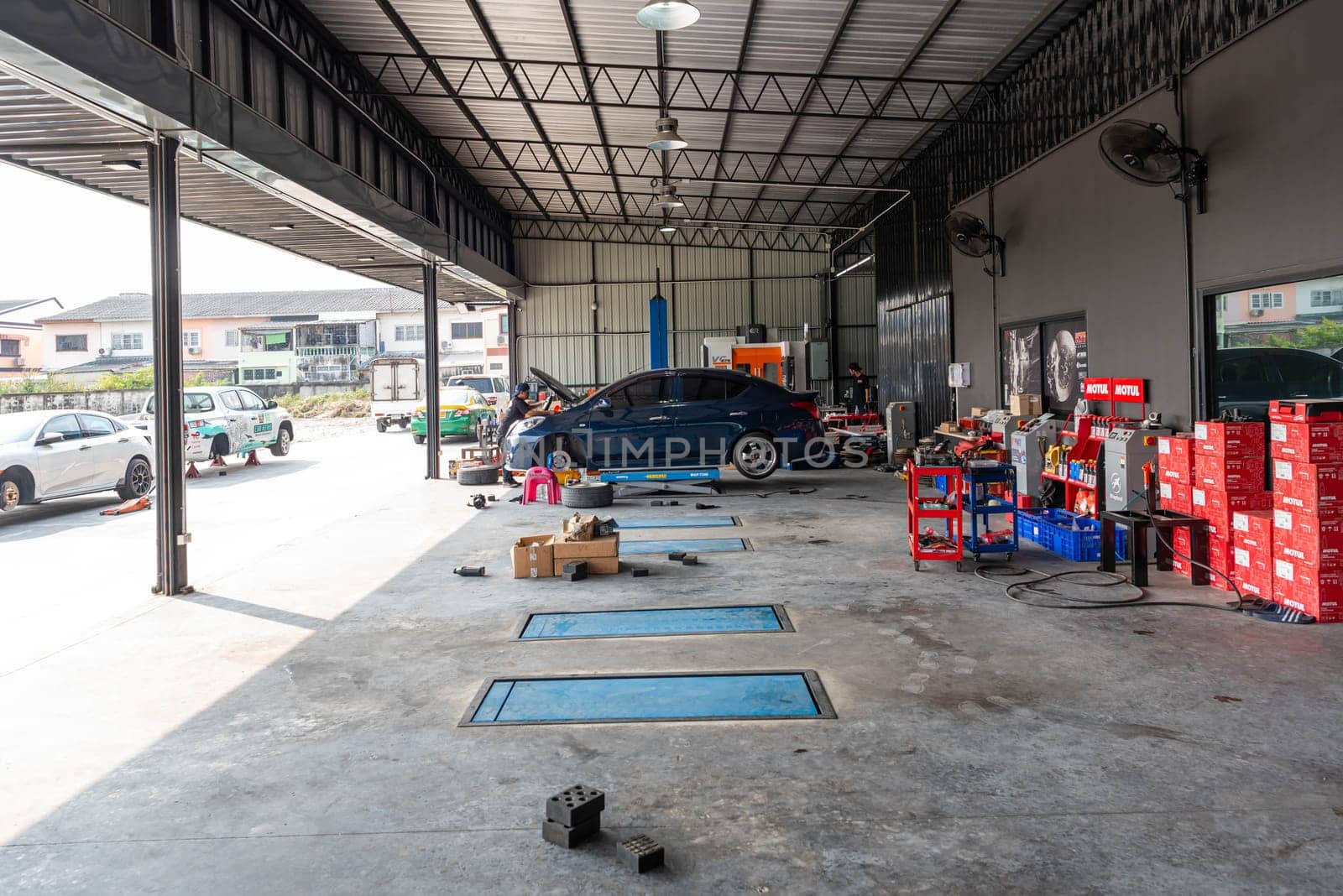 Bangkok, Thailand - February 4, 2023 : Unidentified car mechanic or serviceman disassembly and checking a disc brake and asbestos brake pads for fix and repair problem at car garage or repair shop