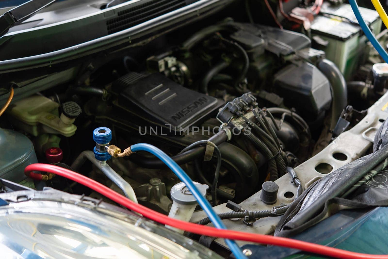 Bangkok, Thailand - May 4, 2023 : Unidentified car mechanic or serviceman refilling air condition and checking a air compressor for fix and repair problem at car garage or repair shop