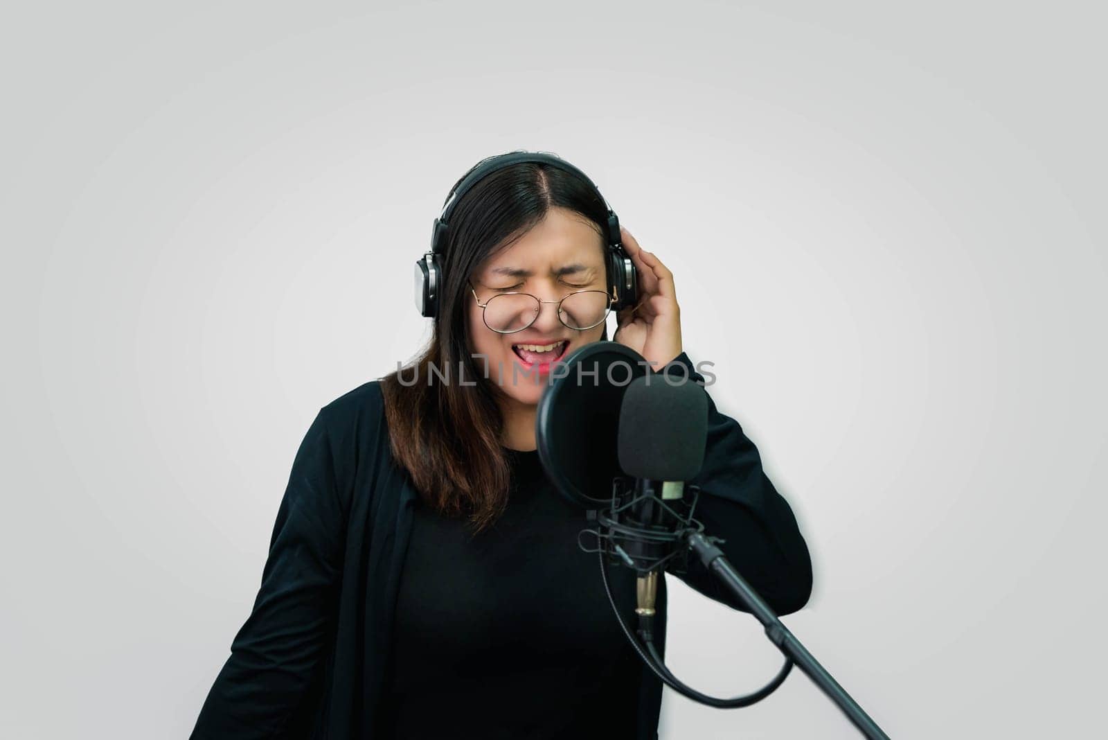 Beautiful asian woman (LGBTQ) is a singer. She enjoying sing a song or karaoke in music studio with microphone condenser and headphones for fun or voice creative