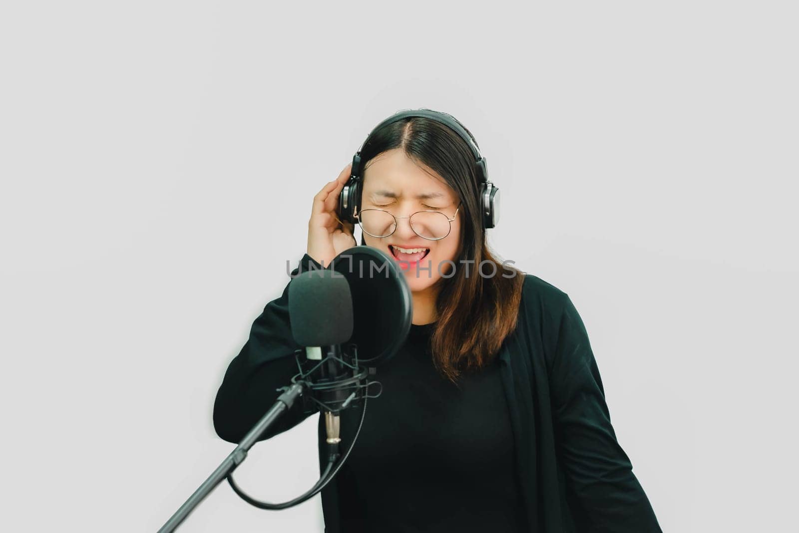 Beautiful asian woman (LGBTQ) is a singer. She enjoying sing a song or karaoke in music studio with microphone condenser and headphones for fun or voice creative