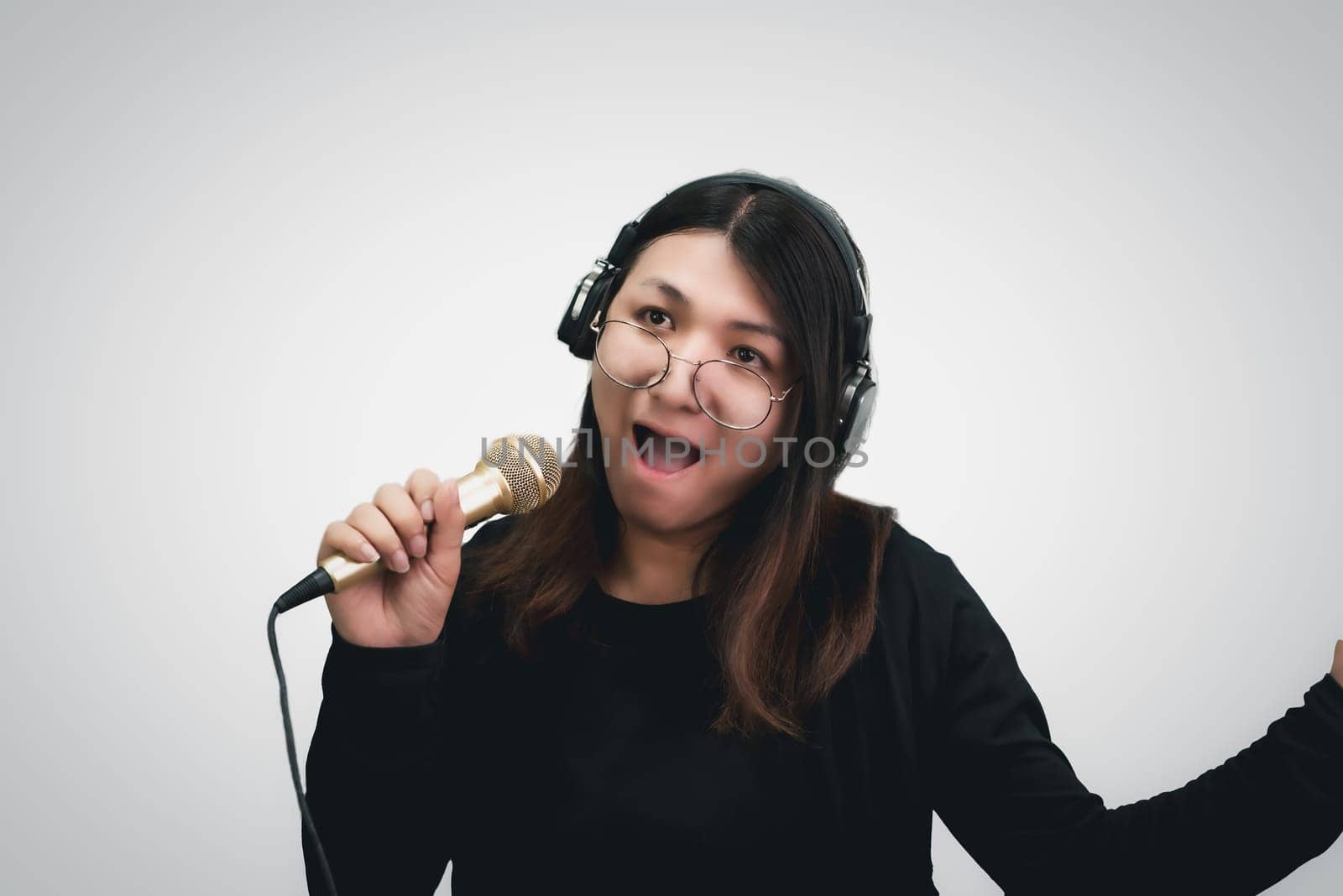 Beautiful asian woman (LGBTQ) is a singer. She enjoying sing a song or karaoke in music studio with microphone condenser and headphones for fun or voice creative