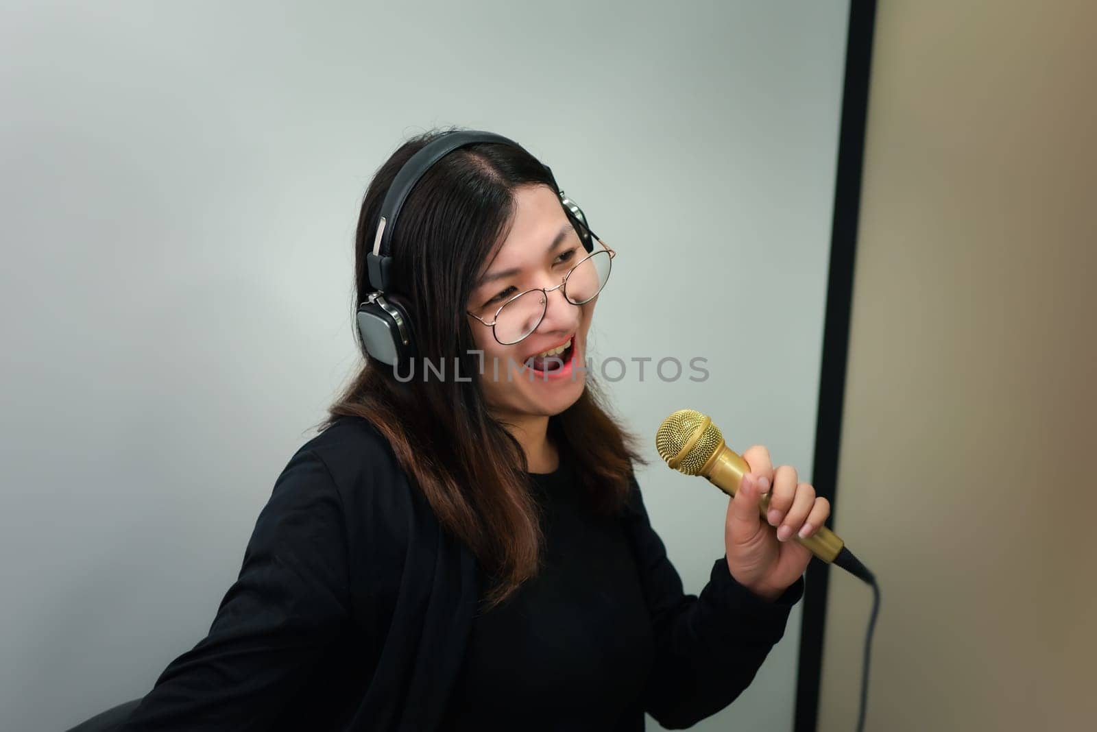 Beautiful asian woman (LGBTQ) is a singer. She enjoying sing a song or karaoke in music studio with microphone condenser and headphones for fun or voice creative