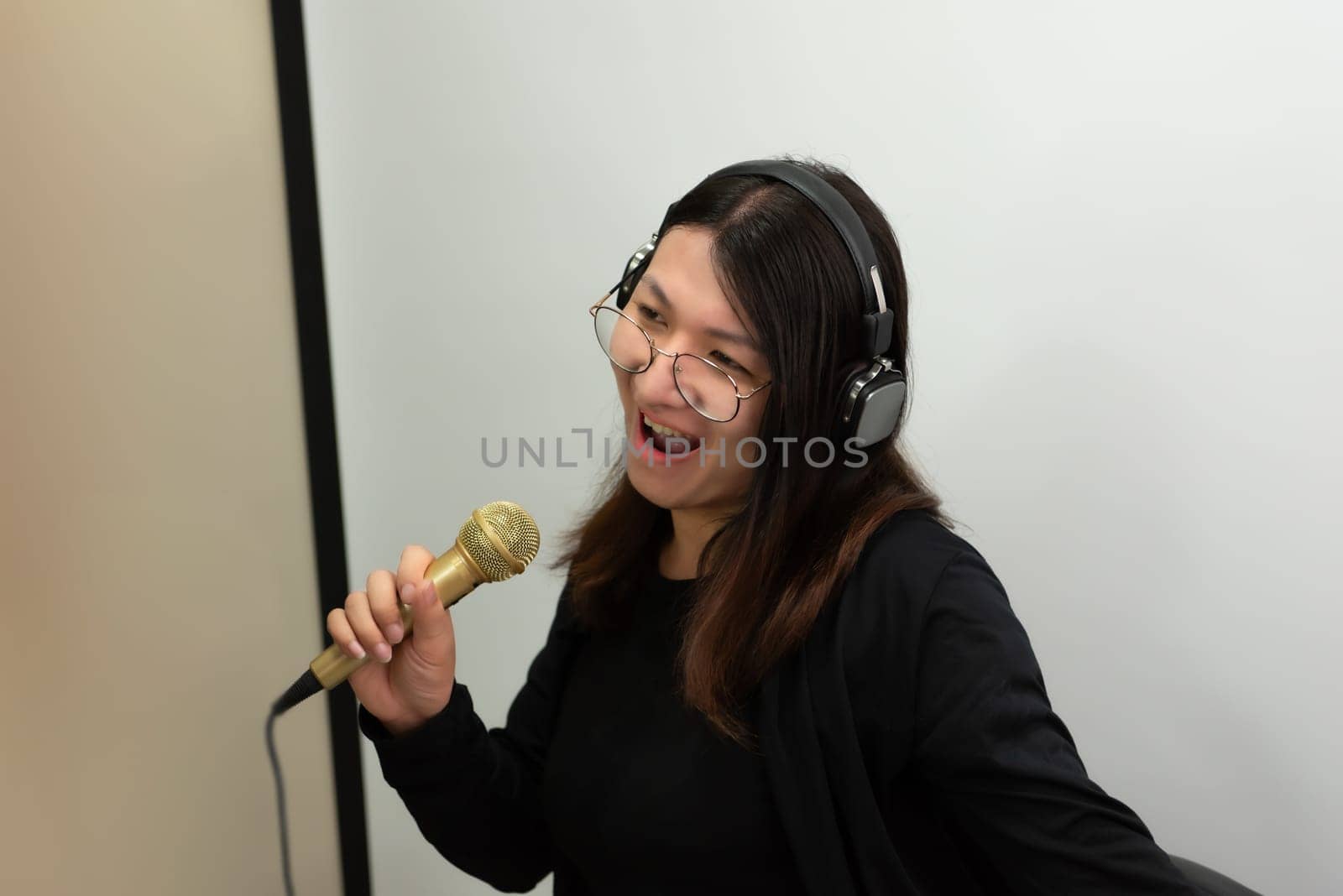 Beautiful asian woman (LGBTQ) is a singer. She enjoying sing a song or karaoke in music studio with microphone condenser and headphones for fun or voice creative